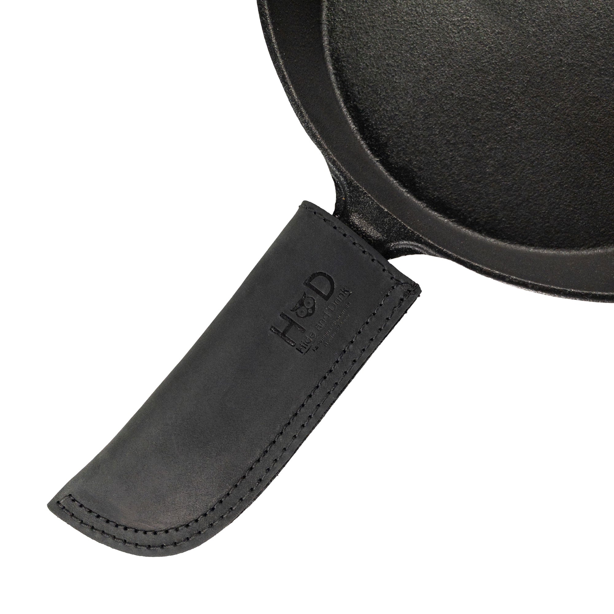 Hide & Drink Cast Iron Panhandle Cover displayed alongside its packaging, emphasizing the details. This artisan hot handle protector is made from double stitched full grain leather and provides superior heat protection. Handmade in La Antigua Guatemala & Oaxaca Mexico, it's perfect for any kitchen setup.