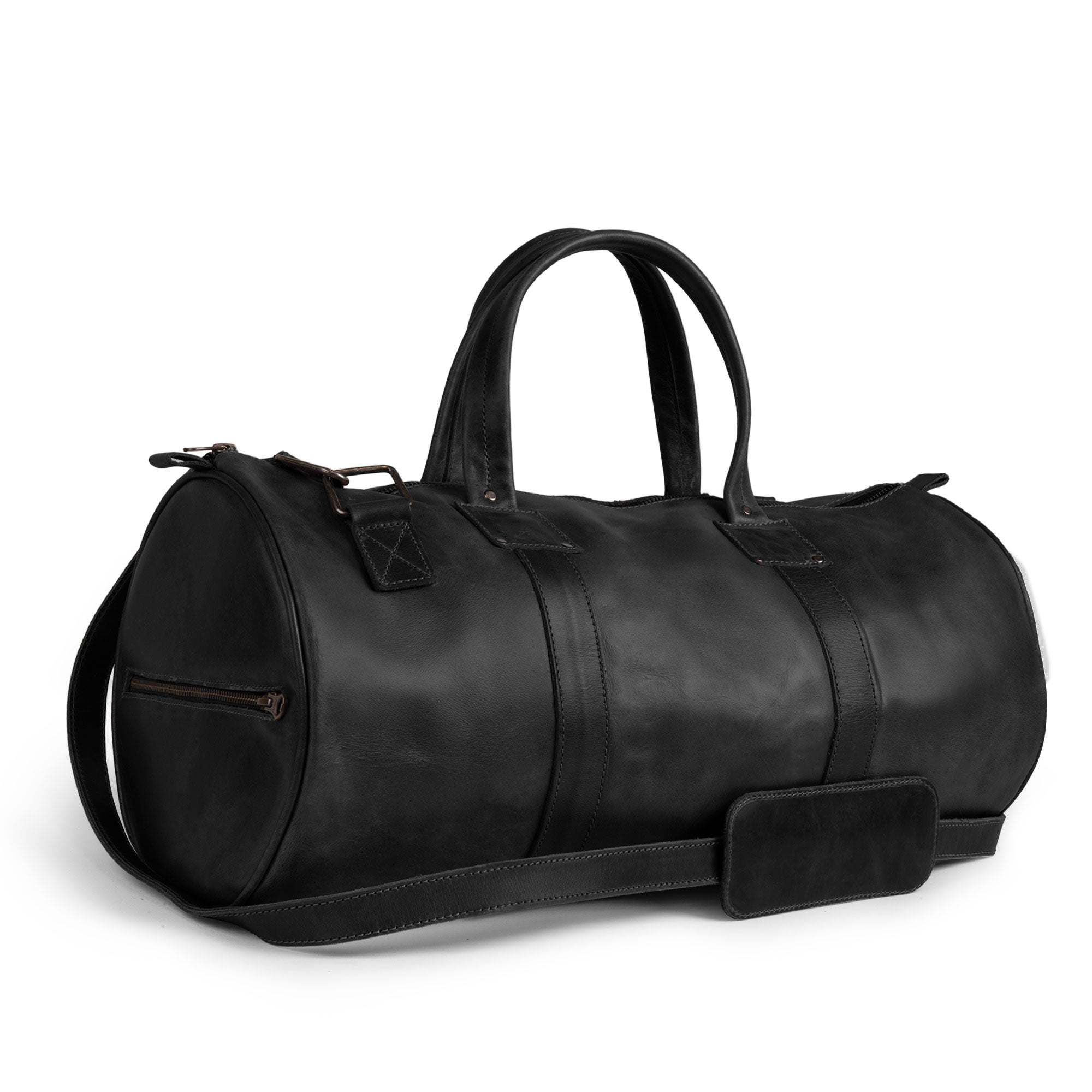 Side view of the Classic Duffle Bag by Hide & Drink in tan leather, highlighting its quality and stylish adjustable strap with zipper closure. This Full Grain Leather Classic Duffle Bag is a versatile Messenger Bag for travel, handcrafted in La Antigua Guatemala & Oaxaca Mexico.