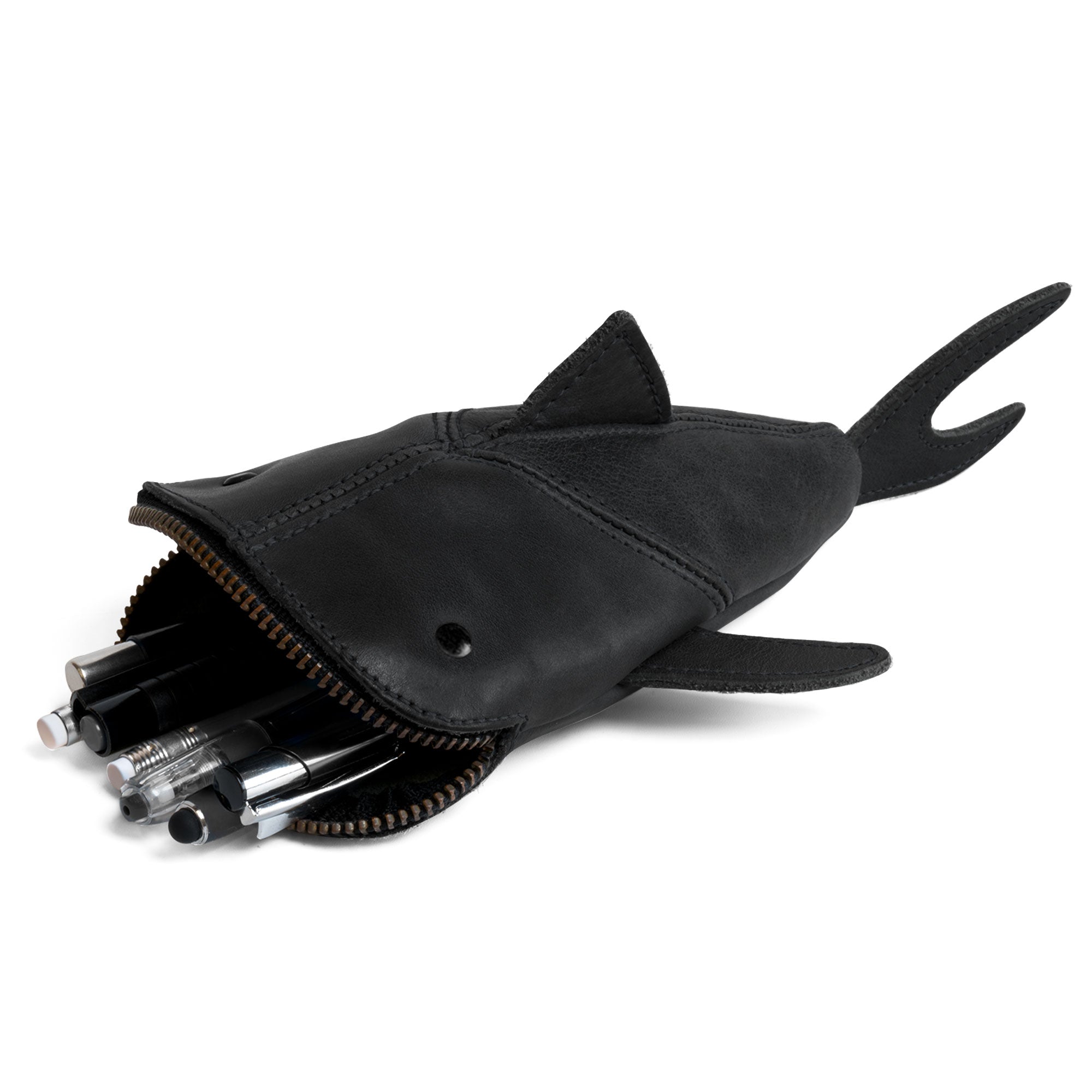 Handmade in La Antigua Guatemala & Oaxaca Mexico Leather Shark Pouch from Hide & Drink, featuring a zippered closure and stuffed with pens. Perfect for organizing art supplies or as a shark shaped case for coins, this full grain leather pouch is artisan-crafted with hand cut and hand sewn precision. Ideal as a change bag or pencil purse, this unique accessory showcases small batch production and fire branded quality.