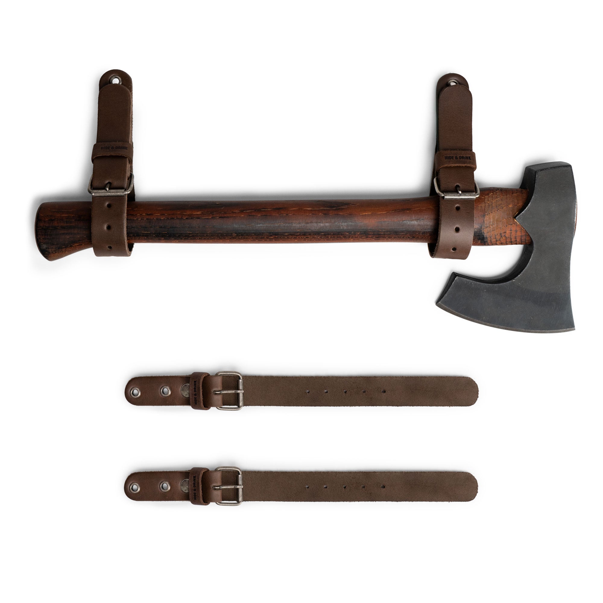 Hide & Drink Wall Hanging Strap showcasing a sturdy thick leather strap featured with an axe, perfect for garage storage organization. This set of 2 heavy-duty tool hangers boasts buckle closure for axes, hatchets & tools, making it an ideal choice for organizing tools. Made from full grain leather, each unit is artisan crafted, hand cut, and hand sewn, emphasizing small batch production in La Antigua Guatemala & Oaxaca Mexico.