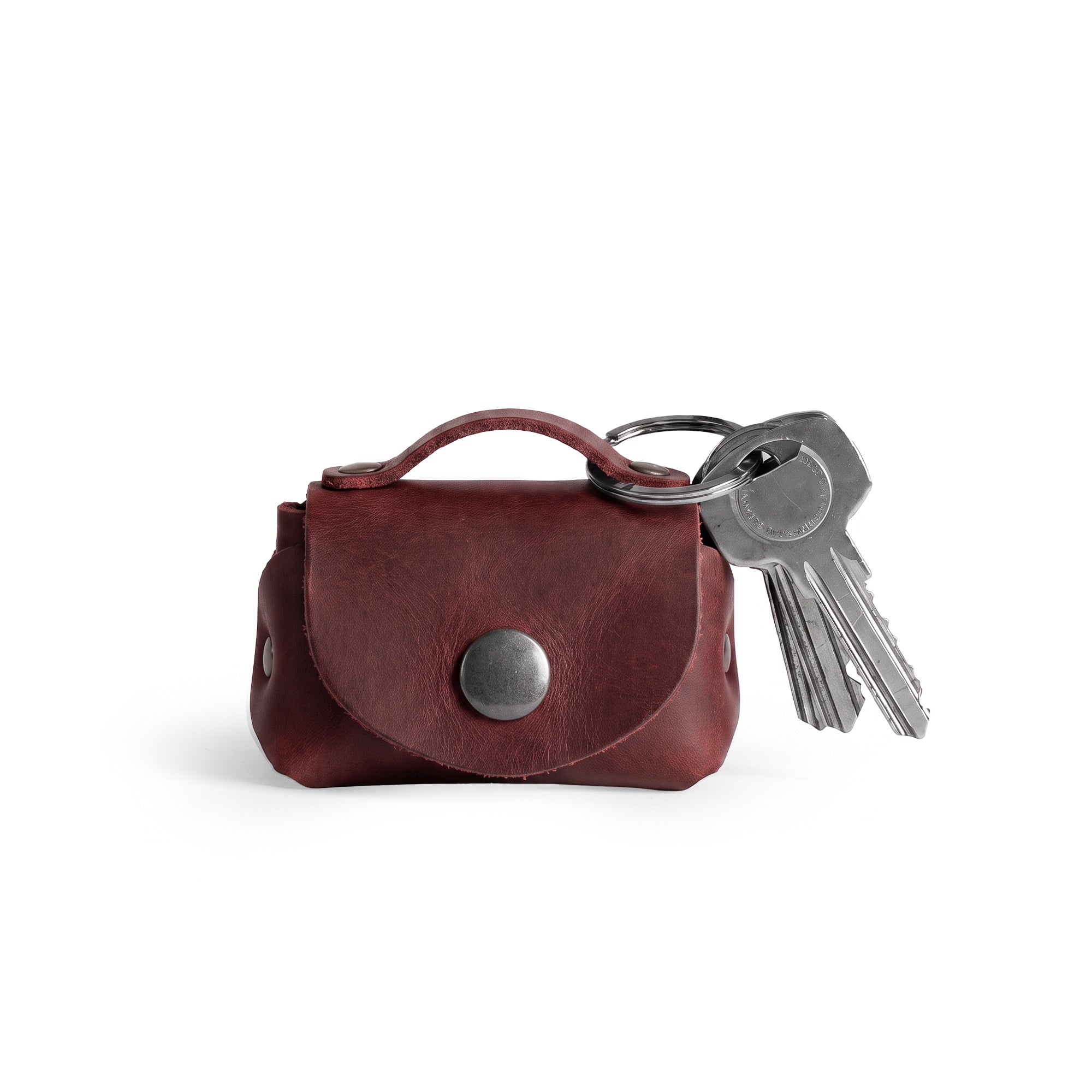 Showcasing the Tiny Handbag Keychain by Hide & Drink, featuring a durable Full Grain Leather design with a key ring holder. This artisanal piece signifies small batch production, showcasing hand cut and hand sewn craftsmanship from La Antigua Guatemala. Perfect for organizing your keys and coins.