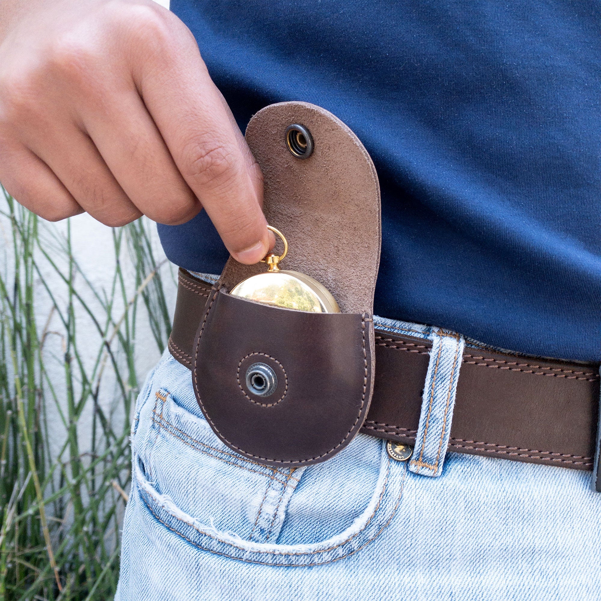 A person inserting a compass into the La Antigua Compass Case, which serves as a stylish carry case for compass. This classic pouch is a protective bag ideal for outdoor accessories, crafted with full grain leather, hand cut and sewn by artisans in La Antigua Guatemala & Oaxaca Mexico.