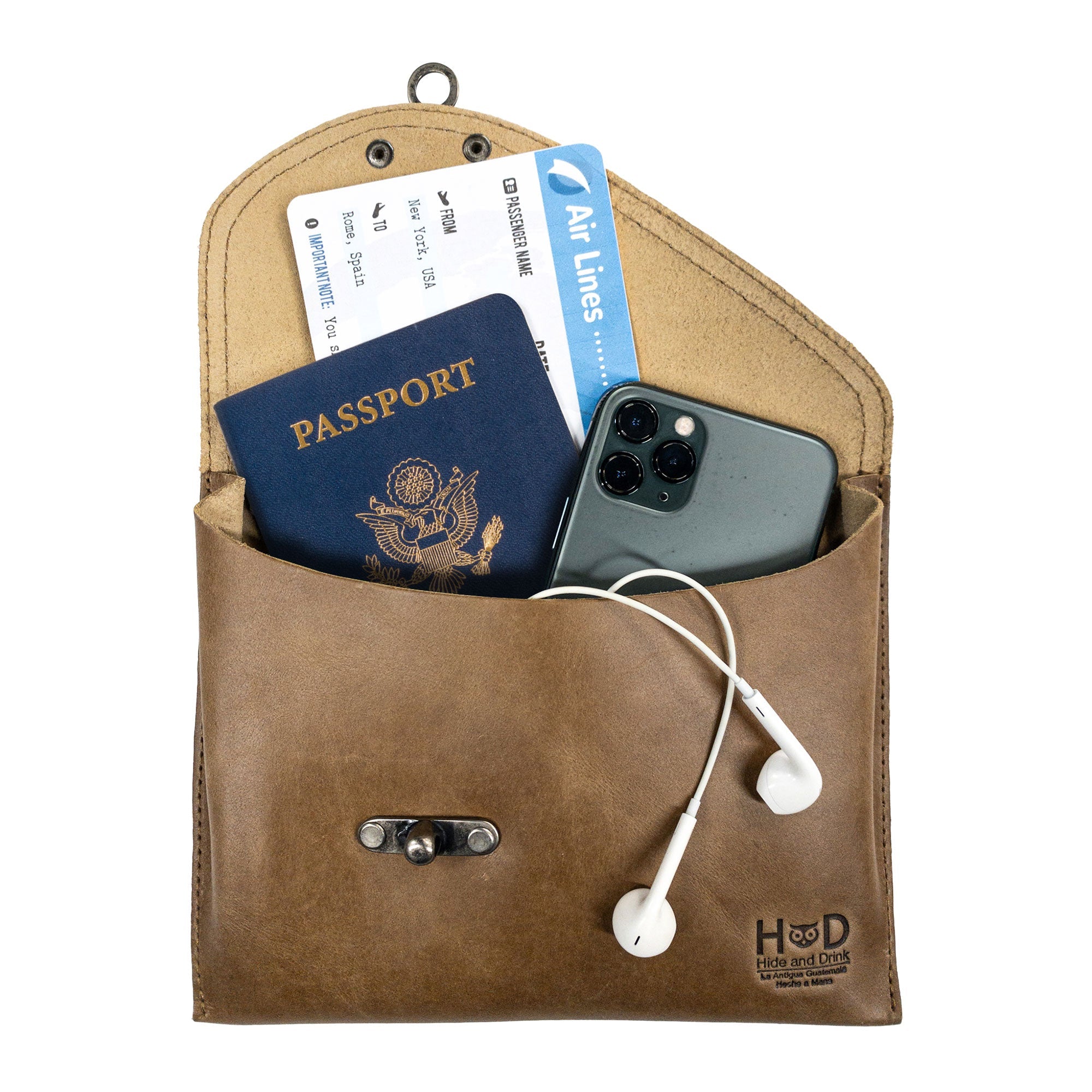 The tan Petite Vintage Clutch Bag by Hide & Drink filled with travel necessities, showcasing its versatility. This chic evening bag made from full grain leather is perfect for those who appreciate handmade artisan products from La Antigua Guatemala & Oaxaca Mexico.