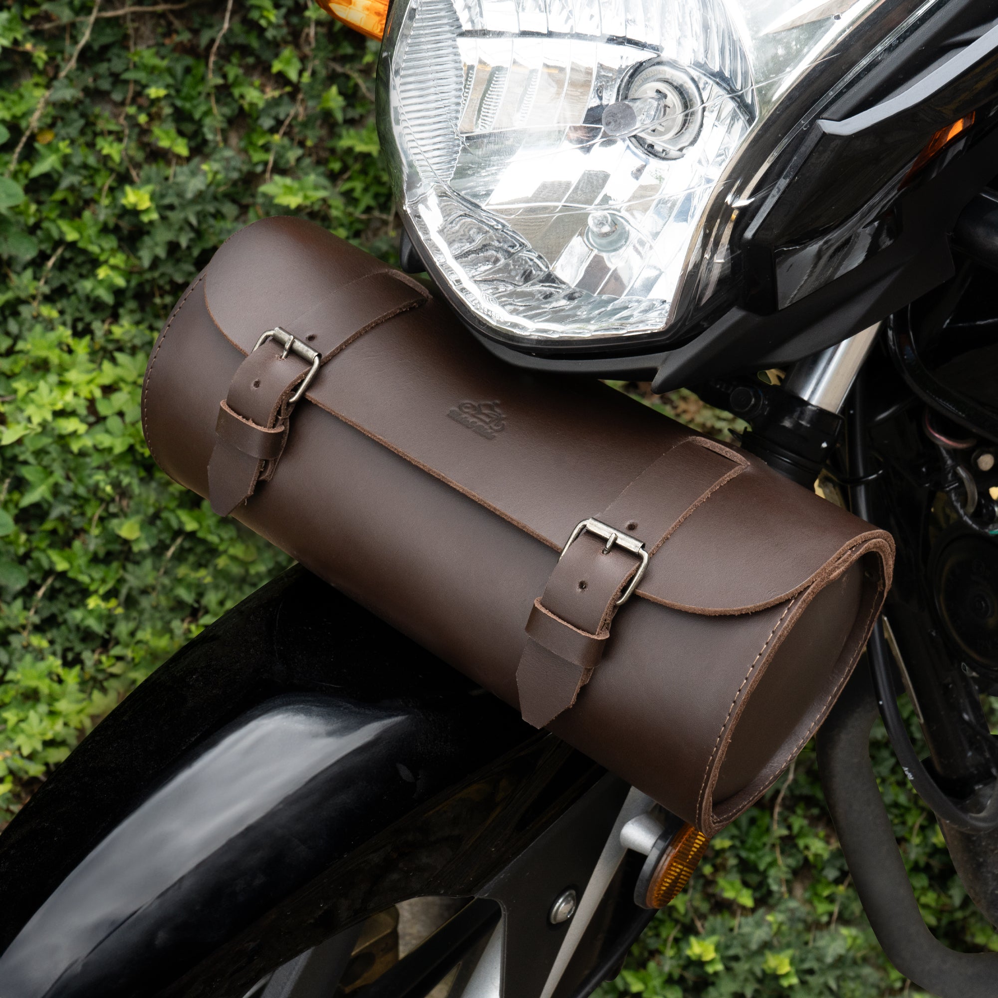 Cylinder Tool Roll for Motorcycle by Hide & Ride, displayed mounted on a motorcycle. This full grain leather tool roll acts as a Circular Motorcycle Tool Bag and showcases its practicality as a universal saddlebag for motorcycle lovers. Handmade in La Antigua Guatemala, it's a reliable fork bag for bikers.