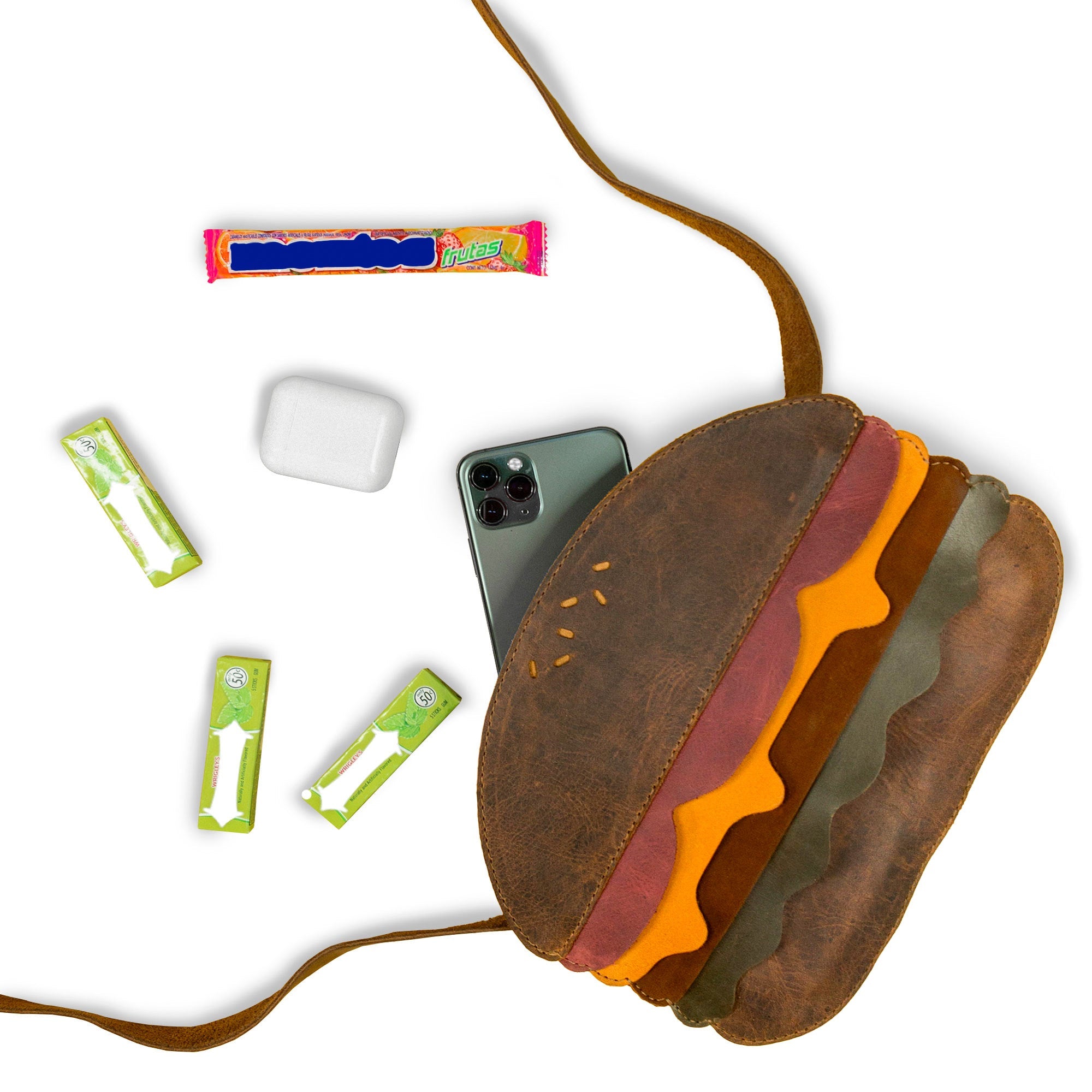 Open Burger-Shaped Shoulder Bag by Tudi Frudi, showcasing its ample storage with included items. This artisanal bag made from Full Grain Leather serves as a fantastic Crossbody Bag and Messenger Bag, adding a playful element to your travel accessories. Carefully crafted in small batches, it's handmade in La Antigua Guatemala & Oaxaca Mexico, perfect for everyday use.