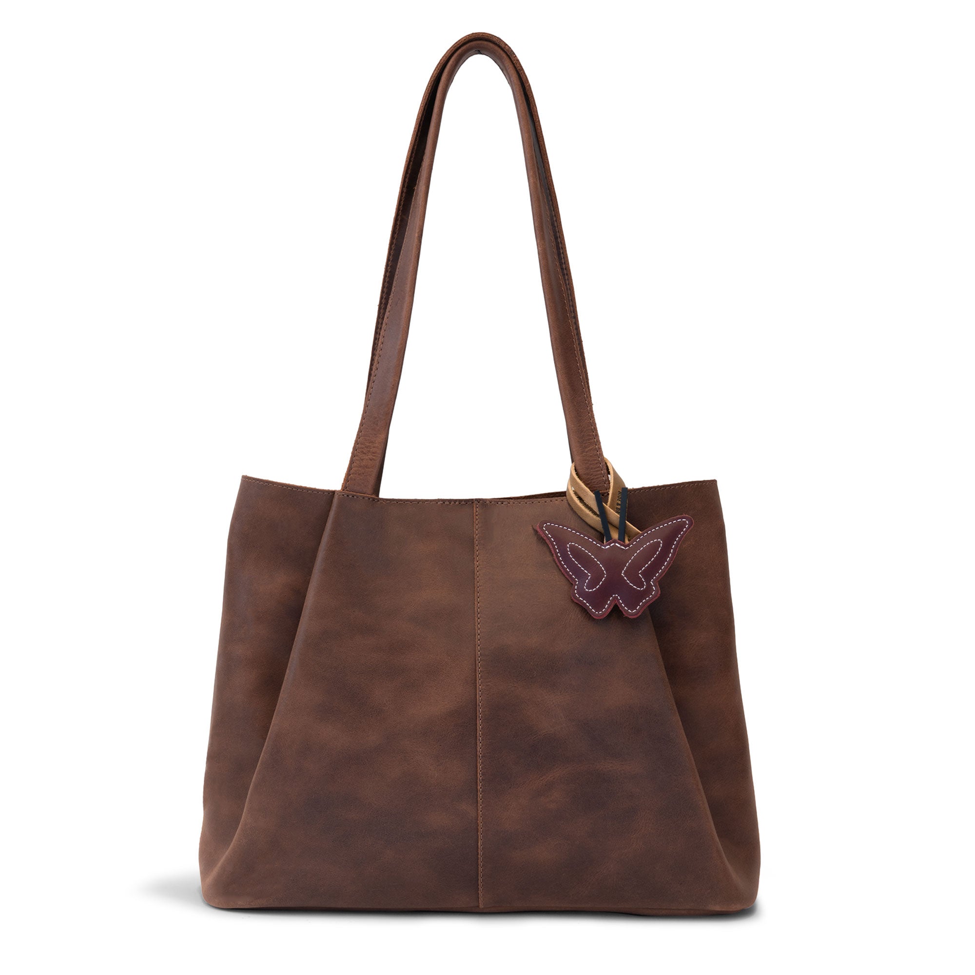 Hide & Drink Bag Charms attached to a trendy brown handbag, showcasing a playful penguin design perfect for personalization. This accessory serves as a purse charm for tote & backpacks made from durable full grain leather, reflecting StockyardX's commitment to small batch production. Every piece highlights hand cut, hand sewn artistry and fire branding, handmade in La Antigua Guatemala & Oaxaca Mexico.