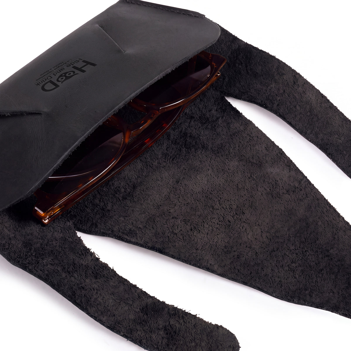 Back view of the black Foldable Sunglass Case by Hide & Drink with a secure closure. Famed for its artisan craftsmanship, this Full Grain Leather case highlights small batch production and fire branding for authenticity.