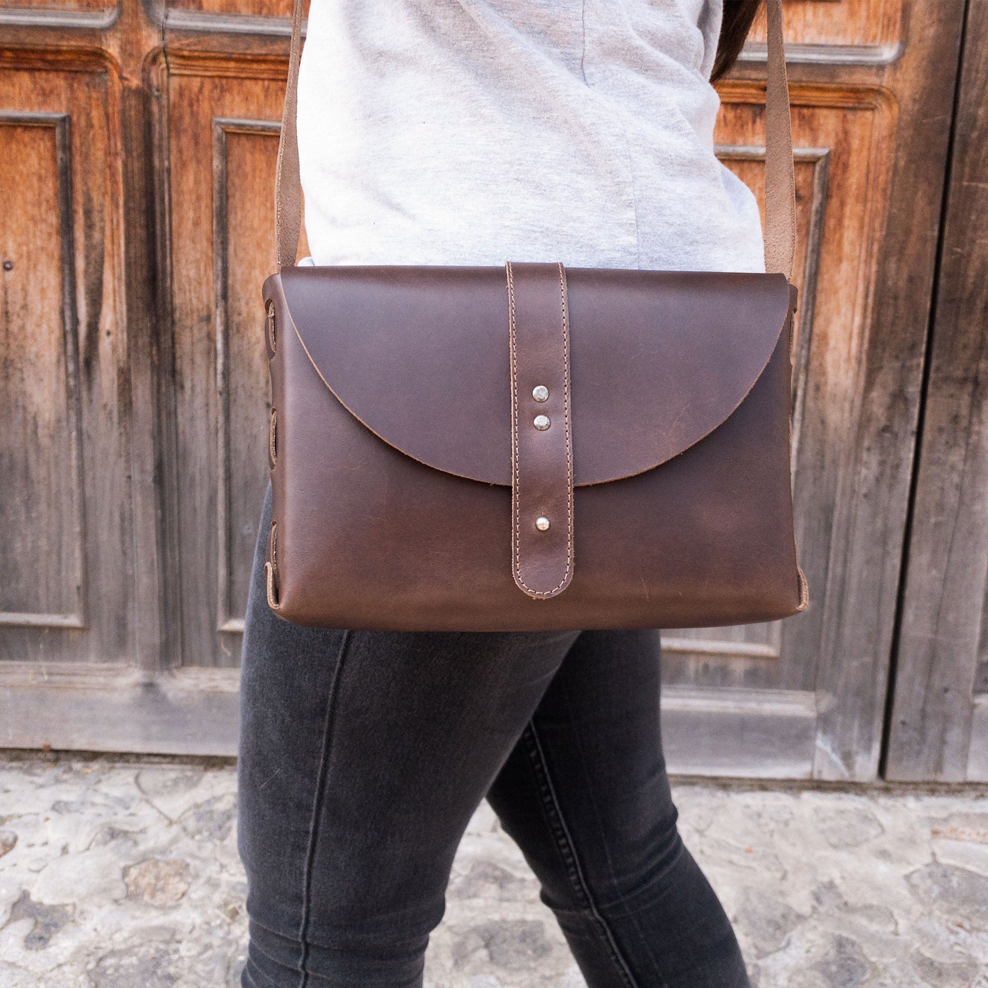 Vintage Leather Satchel by La Antigua, depicted on a model, highlighting the rectangular shape and adjustable strap. This messenger bag, made from full grain leather, adds a touch of classic style while being handmade in La Antigua Guatemala.