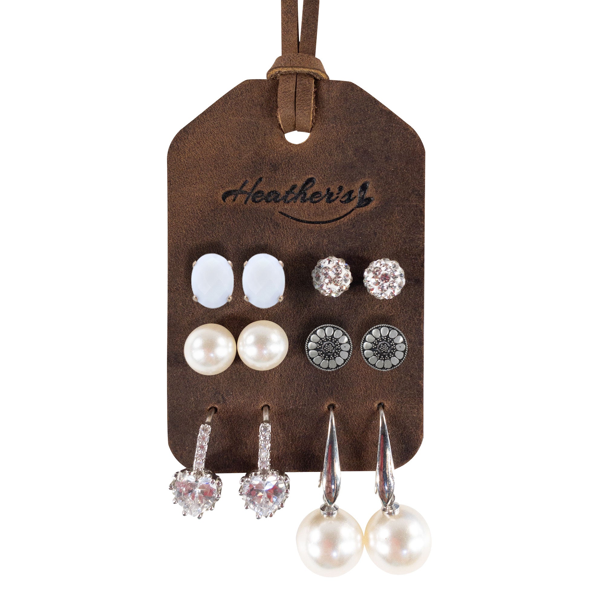 A beautifully organized Set of 2 Earring Tags by Heather's displaying various earrings securely attached through pre-cut holes, designed for easy travel. These display tags are crafted from full grain leather, reflecting artisan quality with hand cut, hand sewn details and fire branded finishes, made in La Antigua Guatemala & Oaxaca Mexico.