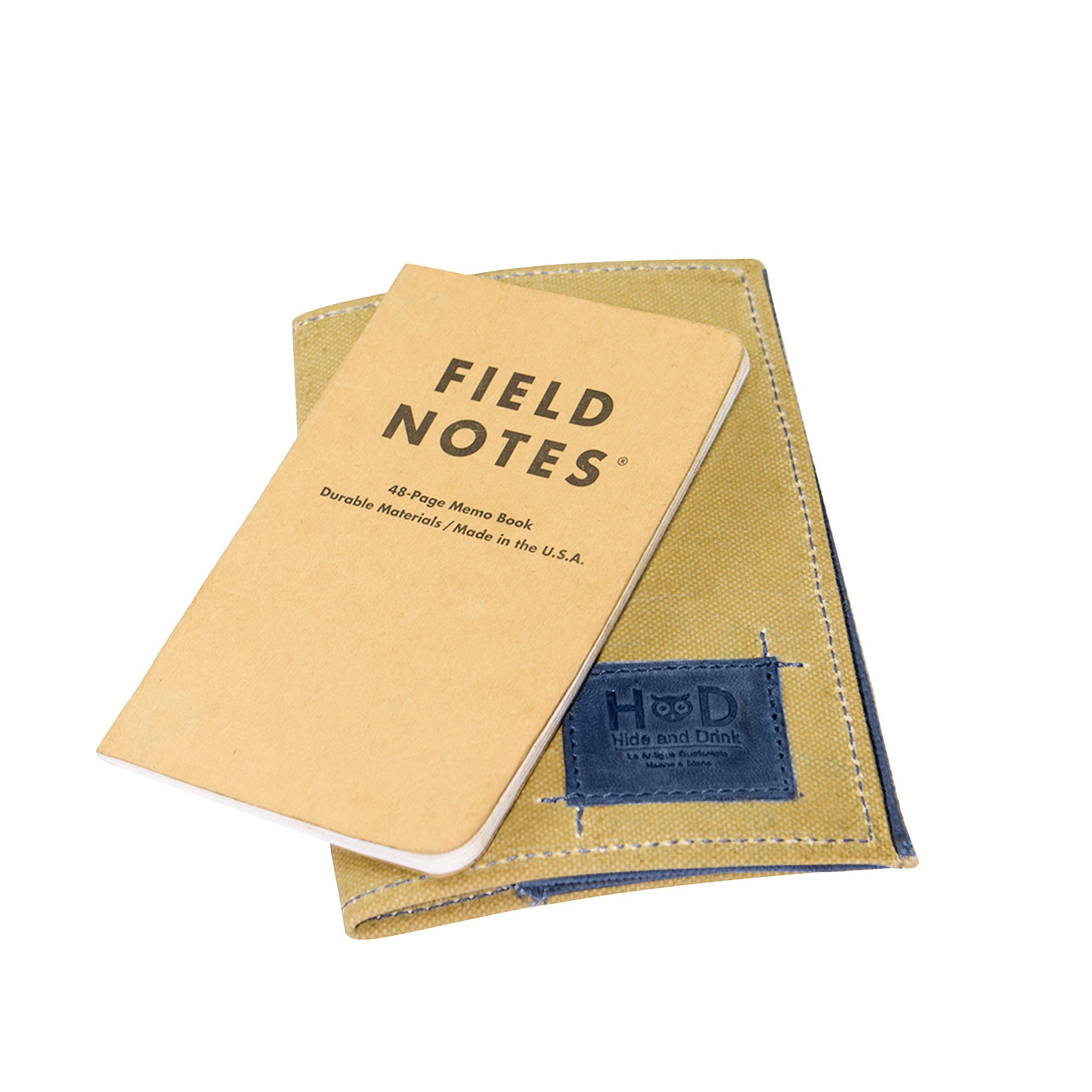 Hide & Drink Waxed Canvas Field Notes Cover displayed in relaxed setting, revealing its stylishness and function. This journal cover offers ample space for notes, cards, and writing instruments, crafted from Full Grain Leather for longevity.
