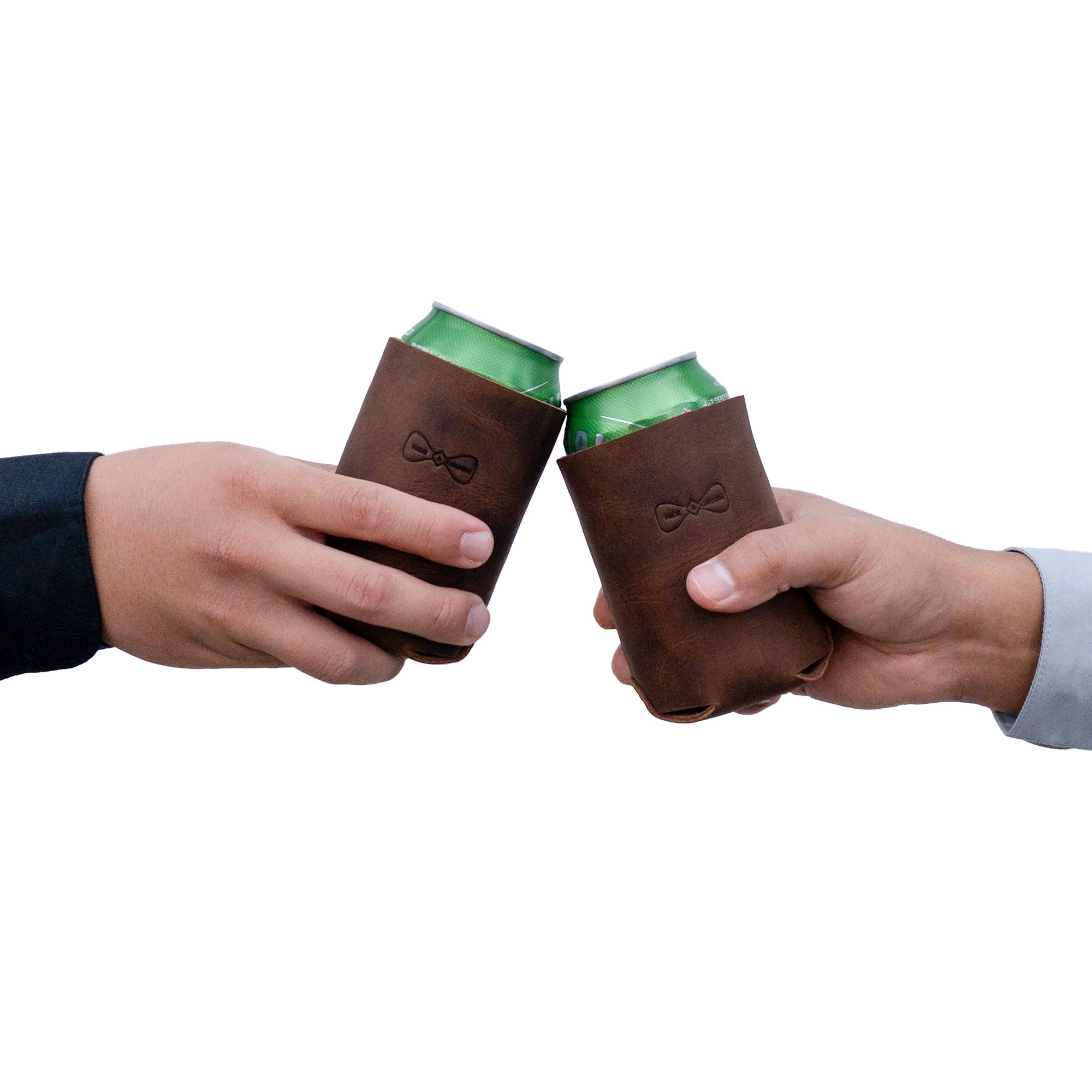 Two hands holding the Hide & Groom Beer Can Sleeve (Set of 2), designed for weddings and parties. These artisan full grain leather sleeves serve as rustic covers for standard cans, combining functionality with style. Handmade in La Antigua Guatemala & Oaxaca Mexico, they are a perfect representation of best man accessories.