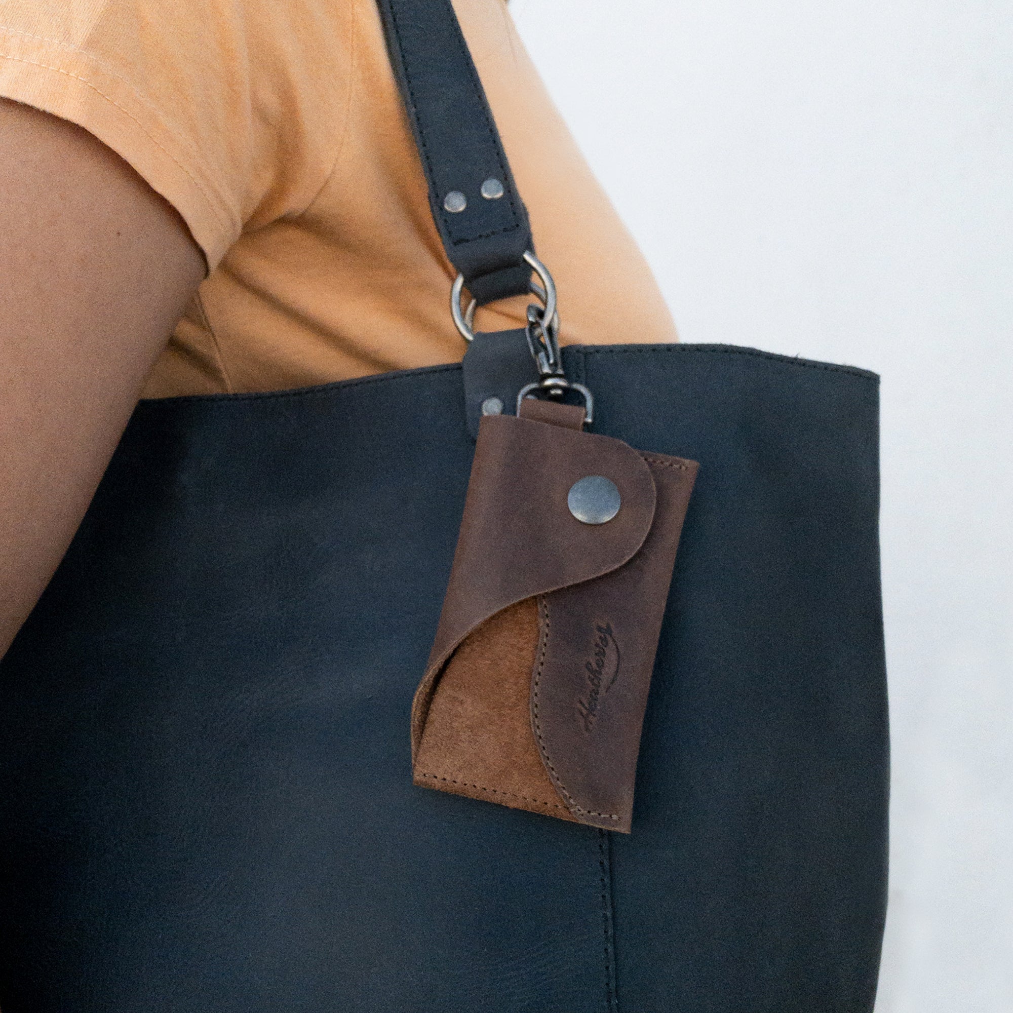 The Female Wallet with Wristlet from Heather's, elegantly attached to a handbag, emphasizing the ID case with wrist strap functionality. This full grain leather wallet works as a money holder and travel organizer, part of an artisan collection made in La Antigua Guatemala and Oaxaca Mexico.