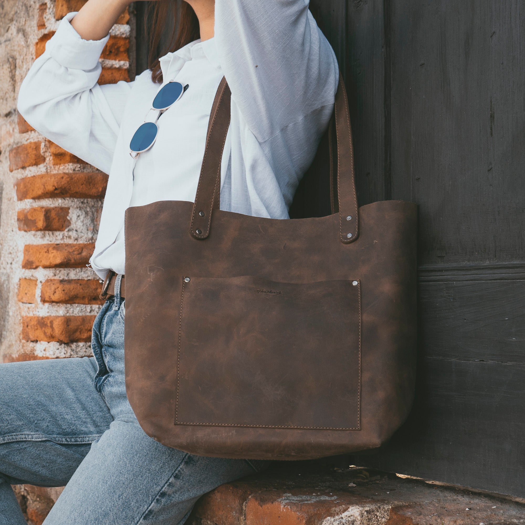 A stylish individual carrying Heather's Minimalist Tote Bag With Pouch, demonstrating its versatility in full grain leather. This Classic Tote Bag Shoulder Bag for Women with Pouch is a handmade treasure from La Antigua Guatemala, showcasing artisan craftsmanship.