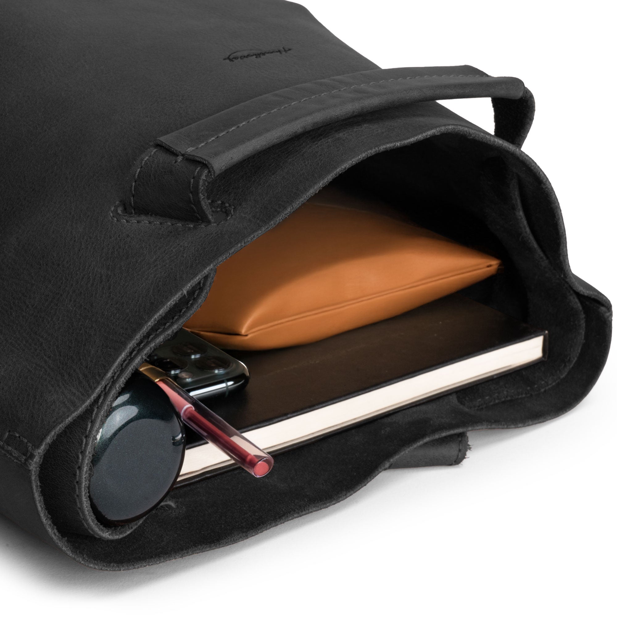 Interior shot of Heather's Convertible Backpack to Shoulder Bag in black, revealing its spacious compartments for everyday items. The bag is crafted from Full Grain Leather, seamlessly transitioning from a squared purse to a backpack, reflecting artisan craftsmanship from La Antigua Guatemala & Oaxaca Mexico.