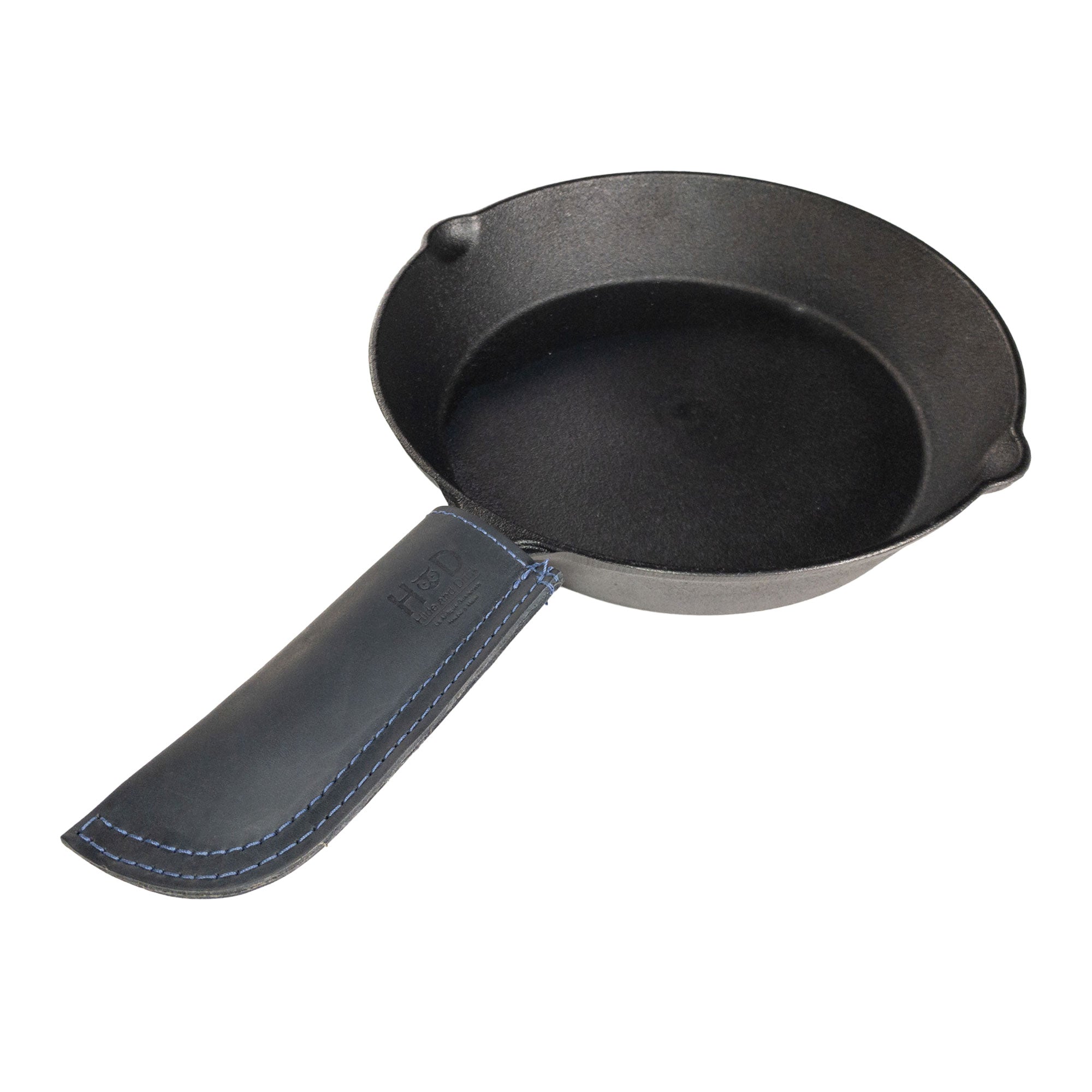Hide & Drink Cast Iron Panhandle Cover elegantly showcased on metal cookware. This durable hot handle protector is crafted from full grain leather and features artisan double stitching. Handmade in La Antigua Guatemala & Oaxaca Mexico, it provides both comfort and safety during cooking.
