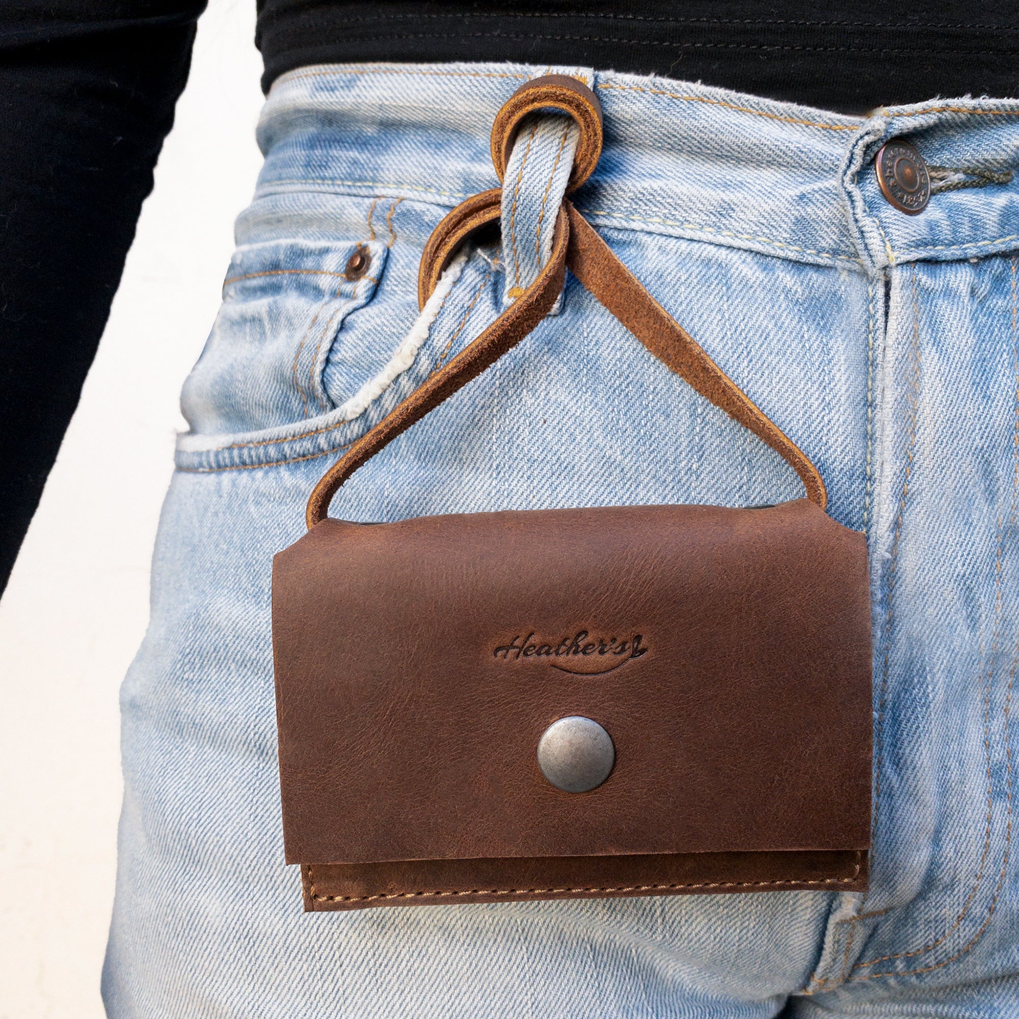 Close-up image of Heather's Mini Purse Wallet attached to jeans, showcasing its practical use as a Mini Wallet Purse with Strap. This card holder provides a stylish money organizer and ID storage, beautifully crafted from full grain leather through small batch production methods, ensuring quality and artisan finesse in every detail.
