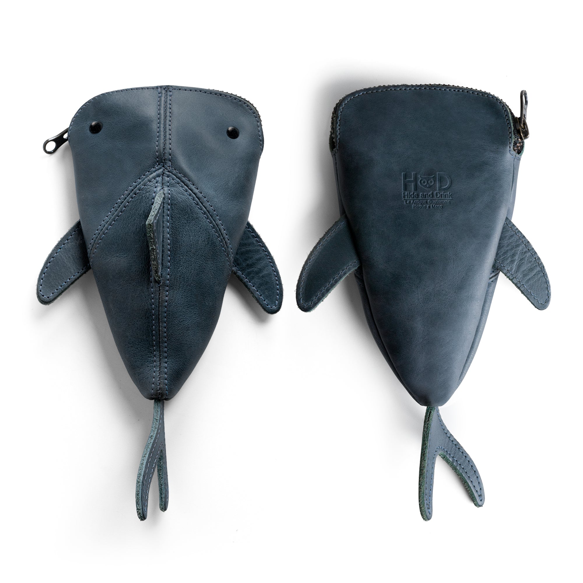 Two views of the Leather Shark Pouch by Hide & Drink, showcasing its playful design. This zippered case is perfect for organizing smaller items like art supplies or coins. Made from full grain leather, it is a charming addition to any space, featuring artisan craftsmanship from La Antigua Guatemala & Oaxaca Mexico.