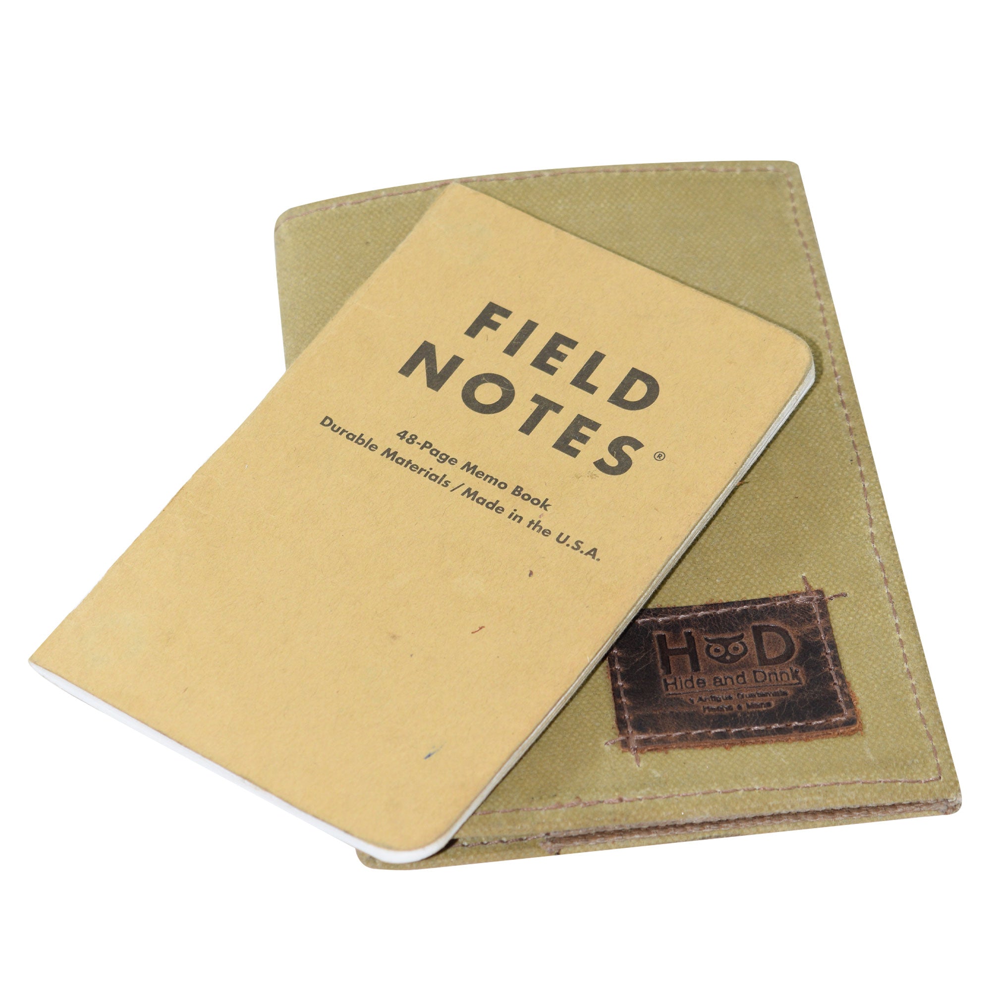 Hide & Drink Waxed Canvas Field Notes Cover alongside a Field Notes notebook, showing off its stylish yet functional capabilities. This product is a compact Wallet Case (3.5 x 5.5 in.) Journal Cover designed for daily use, crafted with Full Grain Leather and an artisan finish.