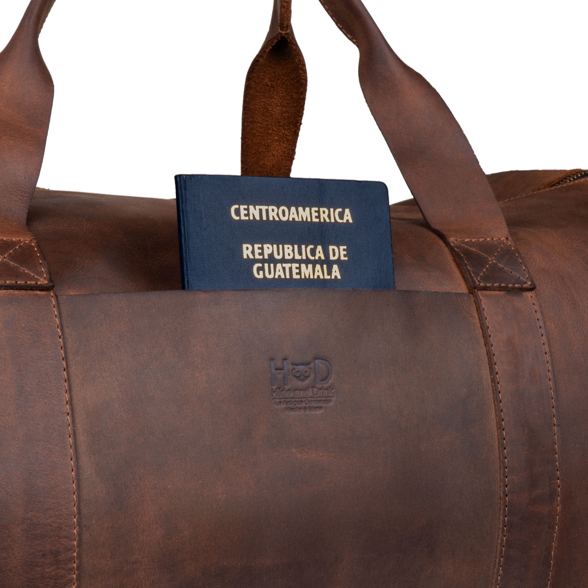Hide & Drink Luggage Duffle Bag with Shoulder Strap with a passport tucked in, demonstrating its stylish yet functional design, crafted from Full Grain Leather as a travel overnight bag, handmade in La Antigua Guatemala & Oaxaca Mexico.