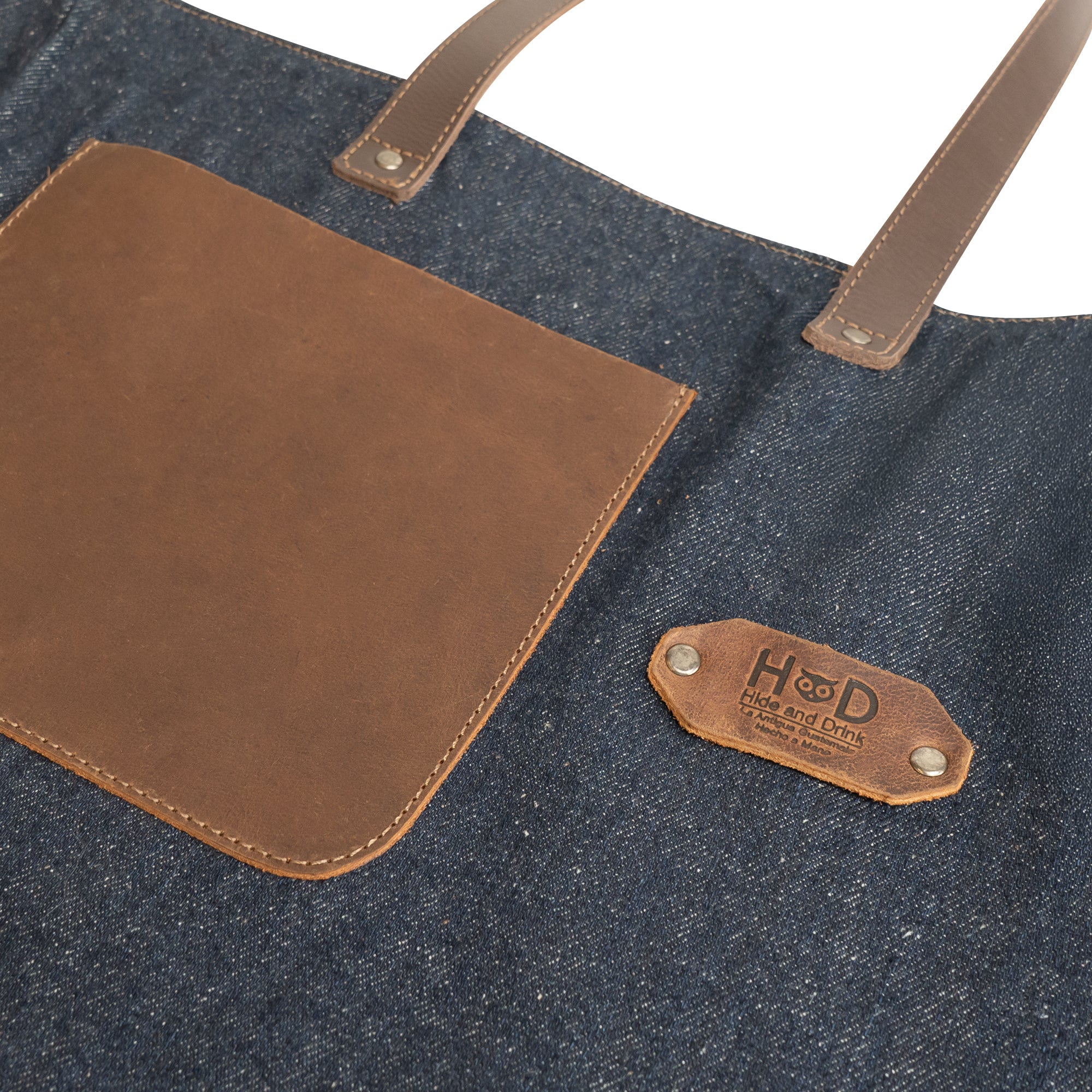 Close-up detail of the Denim Tote Bag with Leather Straps by Hide & Drink highlighting the leather pocket and brand label. Durable Denim Tote Bag with Leather Straps, Cell Phone Purse, Shoulder Bag for Girls, Full Grain Leather, StockyardX, Small Batch Production, Hand Cut, Hand Sewn, Fire Branded, Artisan, Handmade in La Antigua Guatemala & Oaxaca Mexico.