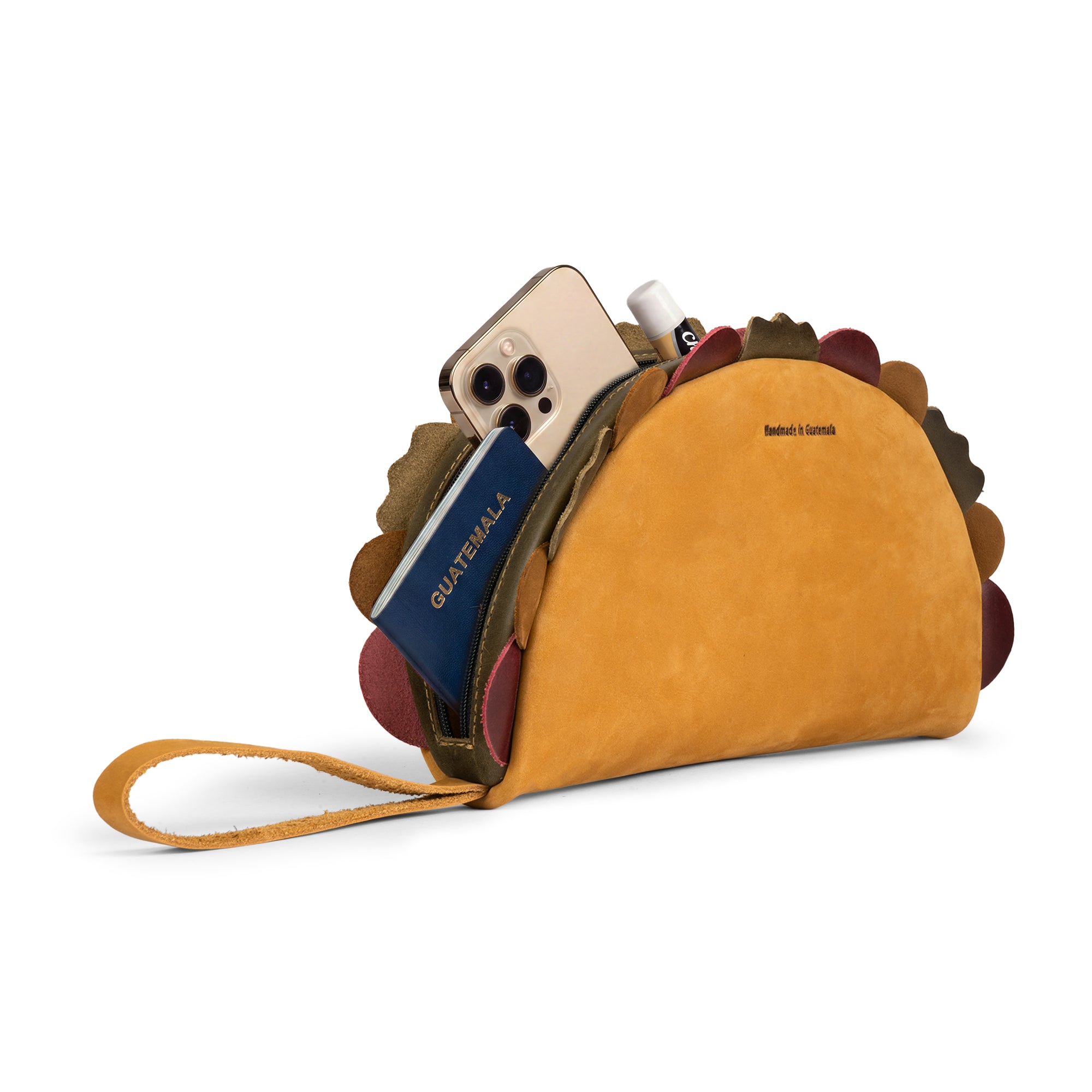 Taco Clutch Bag by Hide & Drink filled with a phone, passport, and small essentials, with its wrist strap extended; Taco Clutch Bag Full Grain Leather from StockyardX, created through Small Batch Production, Hand Cut, Hand Sewn, Fire Branded Artisan work, Handmade in La Antigua Guatemala & Oaxaca Mexico.
