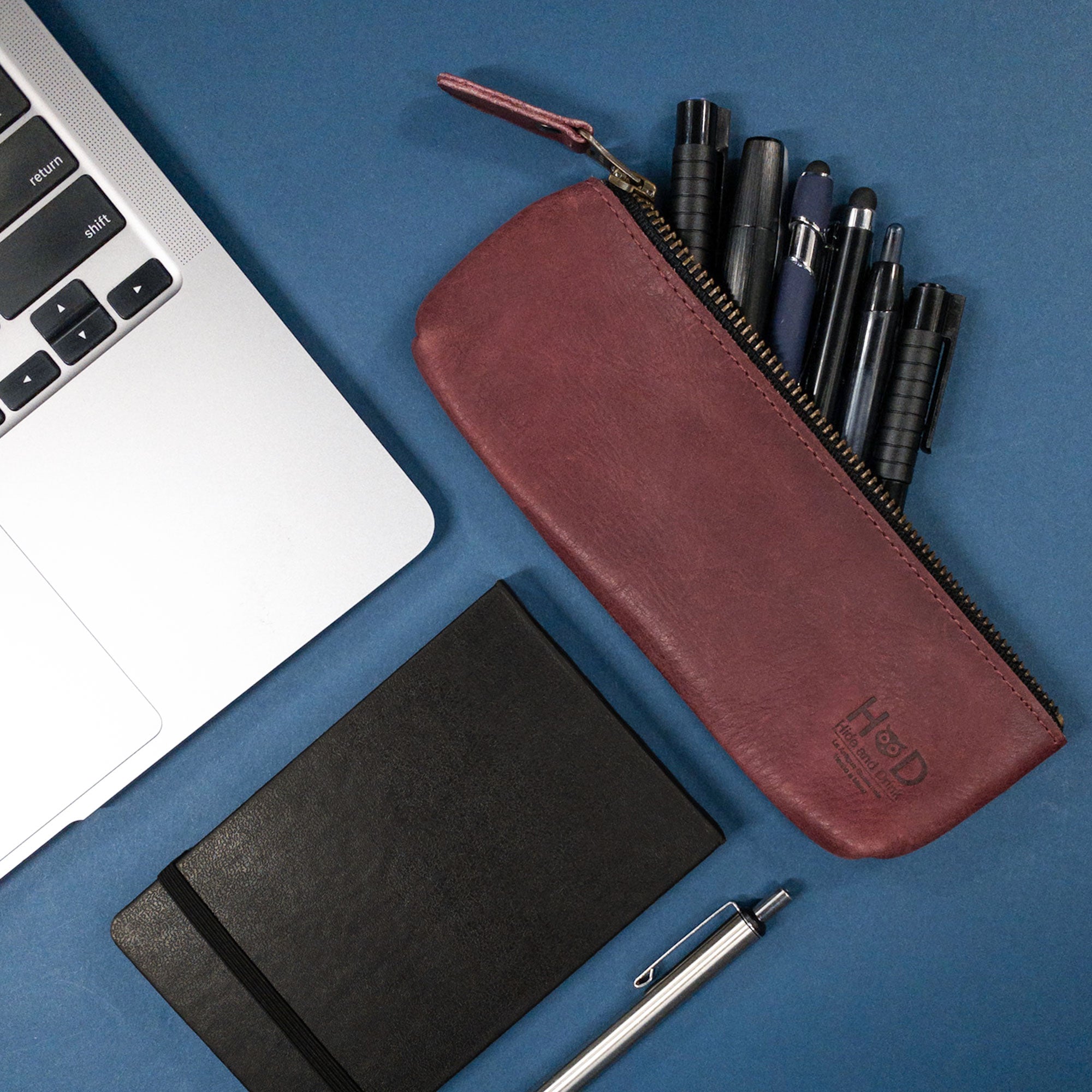 Hide & Drink's Pencil Pouch, artfully arranged with pens and a notebook. This full grain leather Rectangular Pencil Case is ideal as a Pen & Marker Pouch for Men and Women, showcasing classic artisan craftsmanship from La Antigua Guatemala.