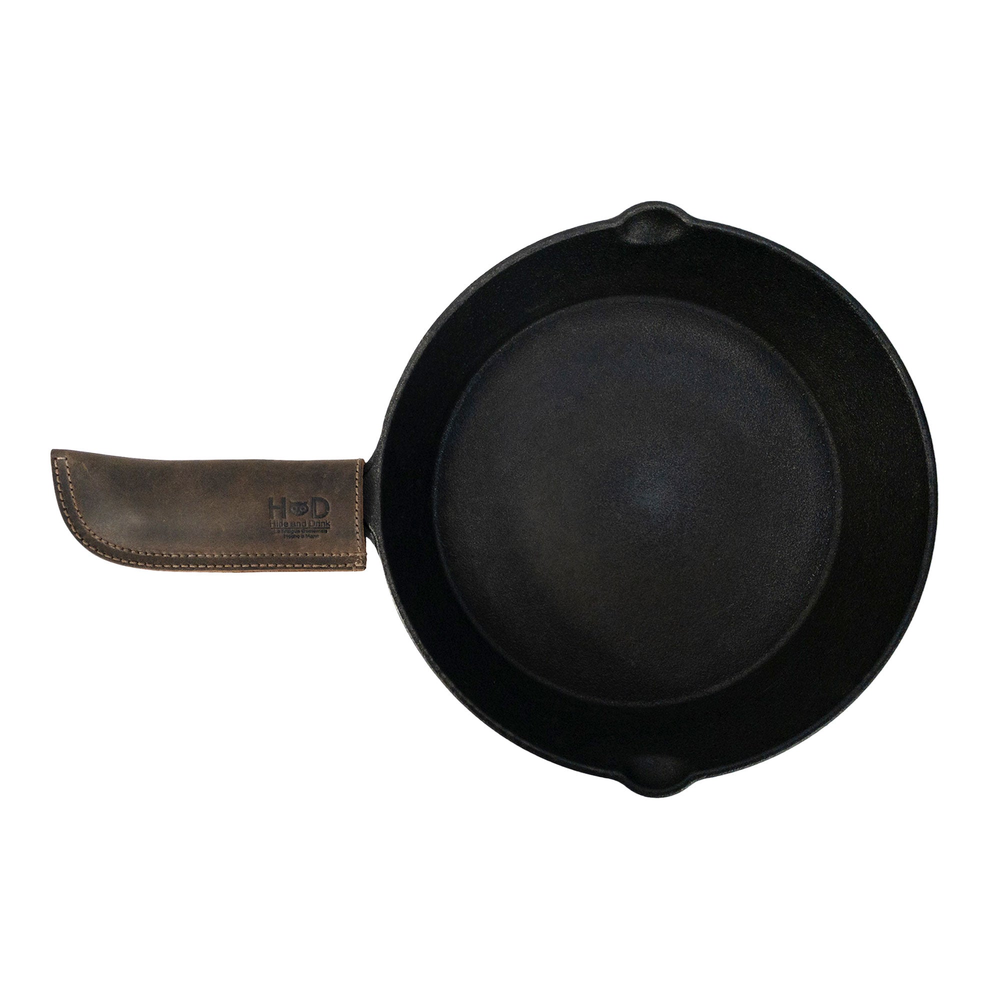 Hide & Drink Cast Iron Panhandle Cover presented artistically, showcasing its craftsmanship. This artisan hot handle protector is designed from durable full grain leather with double stitching for optimal strength. Handmade in La Antigua Guatemala & Oaxaca Mexico, it's a kitchen essential for any cooking enthusiast.