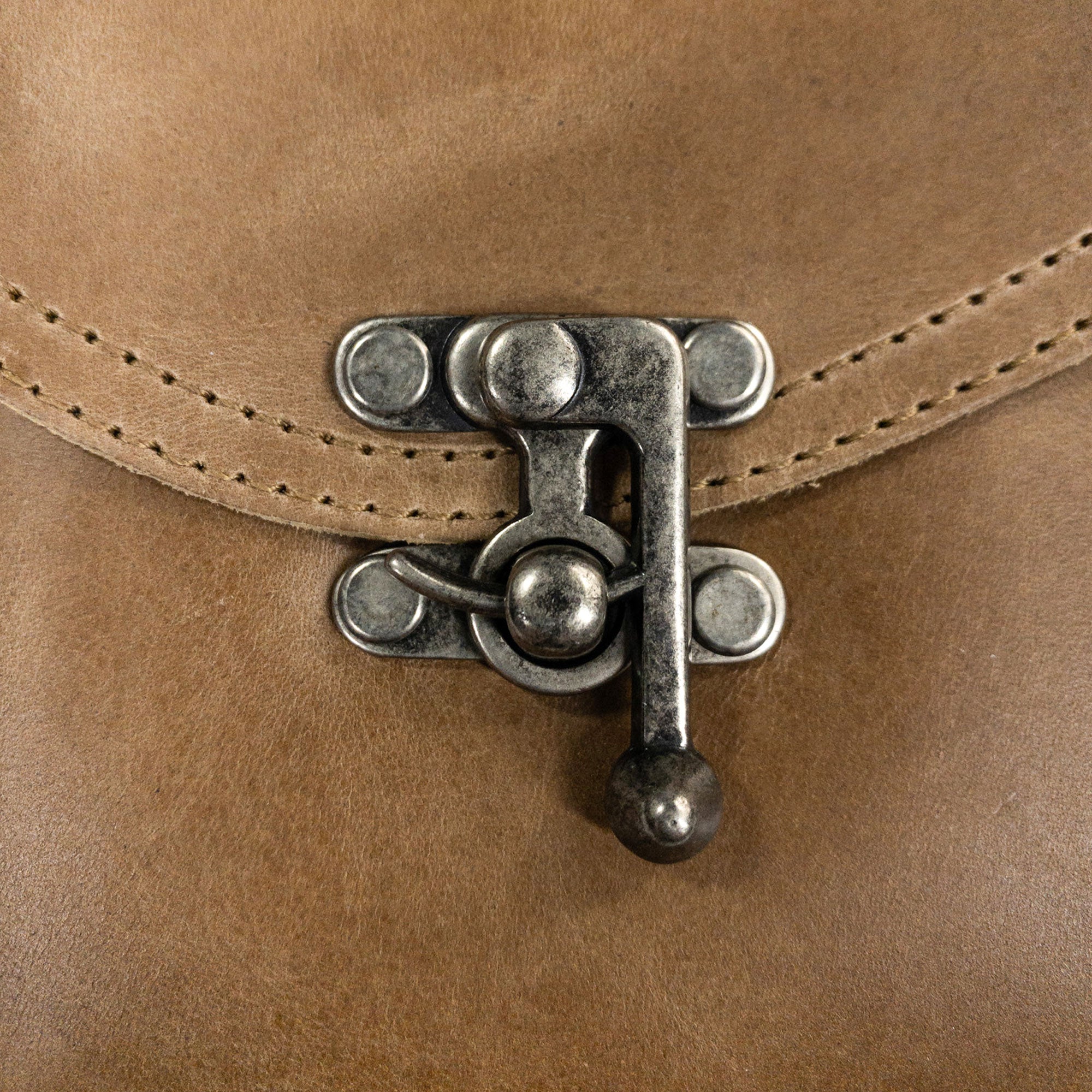 Close-up on the vintage clasp of the tan Petite Vintage Clutch Bag by Hide & Drink, showcasing meticulous craftsmanship. This stylish handbag, made from full grain leather, serves as an elegant evening bag or travel accessory, proudly artisan-made in La Antigua Guatemala & Oaxaca Mexico.
