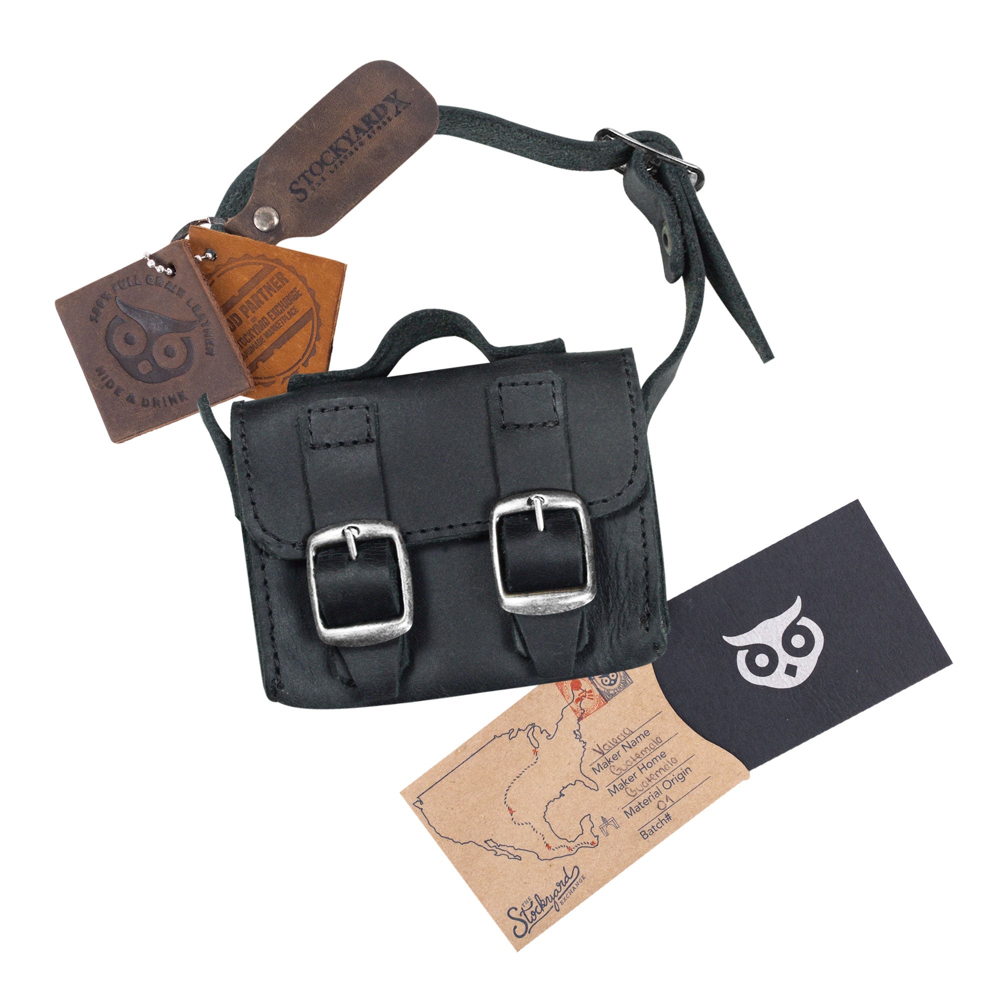 The Black Tiny Messenger Bag by Hide & Drink, featured with accompanying tags. This Mini Messenger Bag Charm, crafted from quality Full Grain Leather, serves as an elegant keychain or handbag accessory. Artisan-made in La Antigua Guatemala, reflecting small batch craftsmanship.