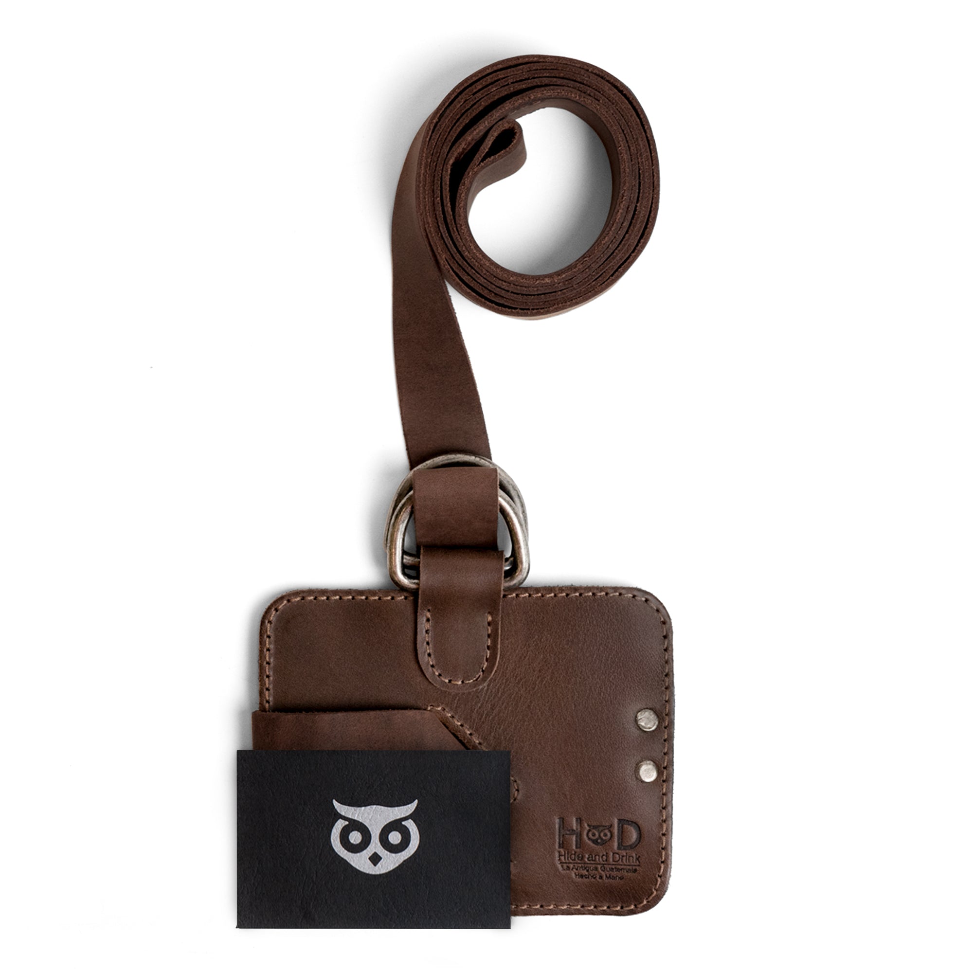 The Hide & Drink Book Strap Carrier alongside a booklet, showcasing the brand logo and design. This Full Grain Leather accessory is a perfect fit for anyone looking to carry books in style, handcrafted by artisans in La Antigua Guatemala.