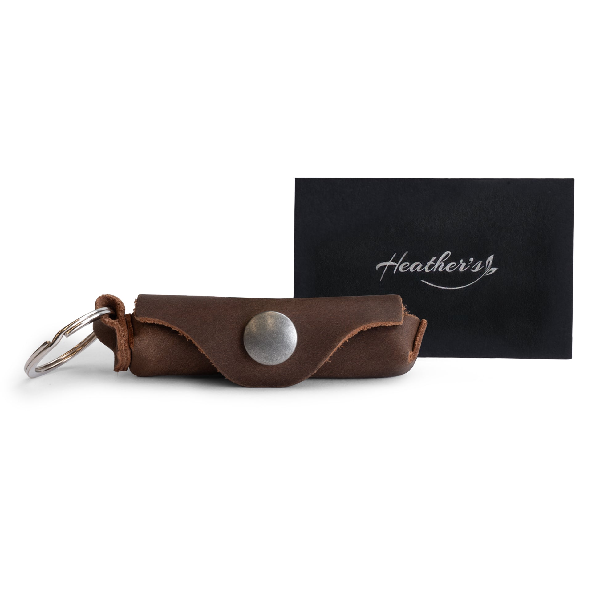 Heather's Lip Balm Keychain - A beautifully packaged Lip Balm Keychain with accompanying tags showcasing its artisan heritage. This Full Grain Leather keychain holder is handmade for travel convenience and perfect for everyday lips protection, making it an excellent gift for loved ones exploring the world.