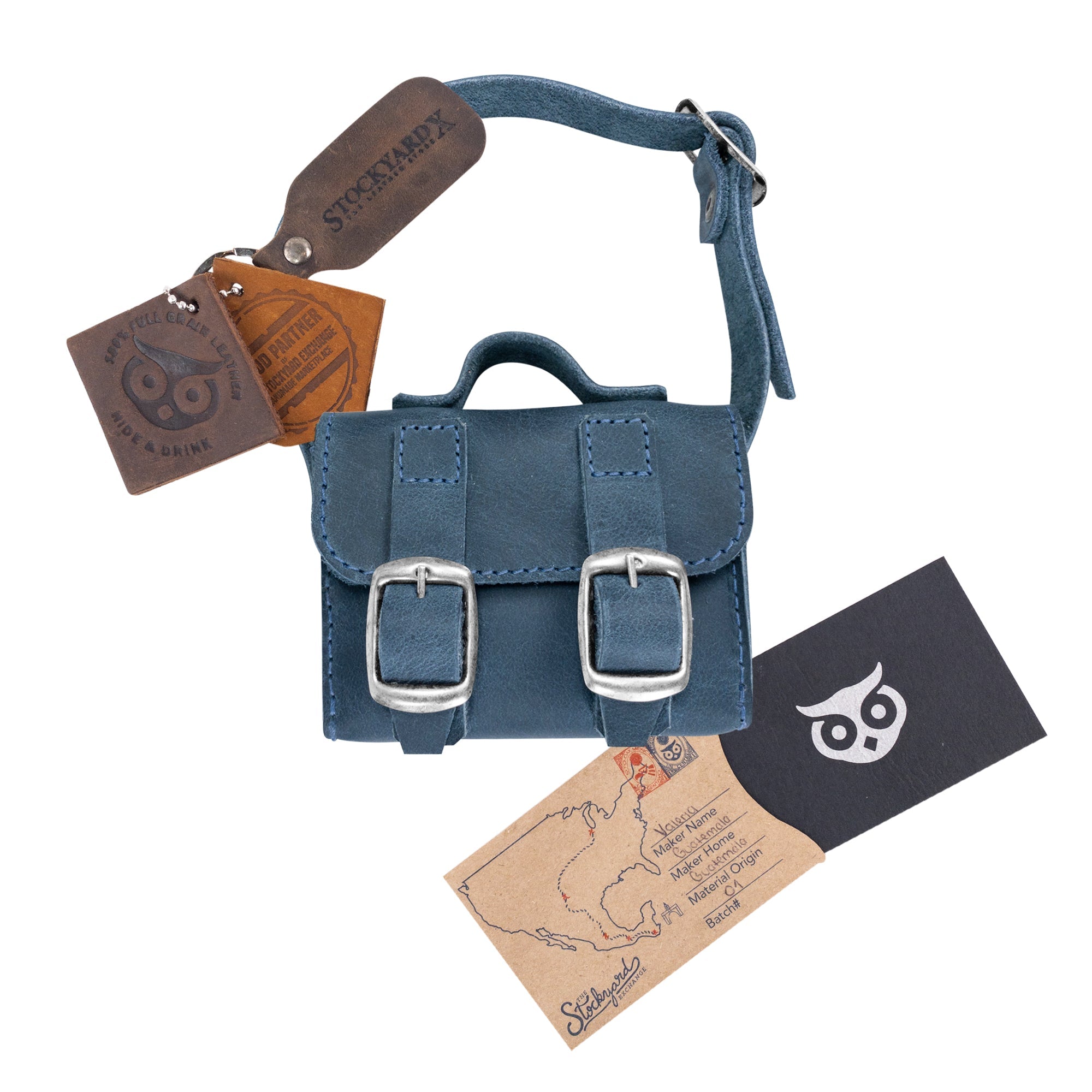 The deep blue Tiny Messenger Bag by Hide & Drink, presented with its tags. This artisan Mini Messenger Bag Charm in Full Grain Leather serves as an excellent keychain or handbag accessory, handcrafted in La Antigua Guatemala.