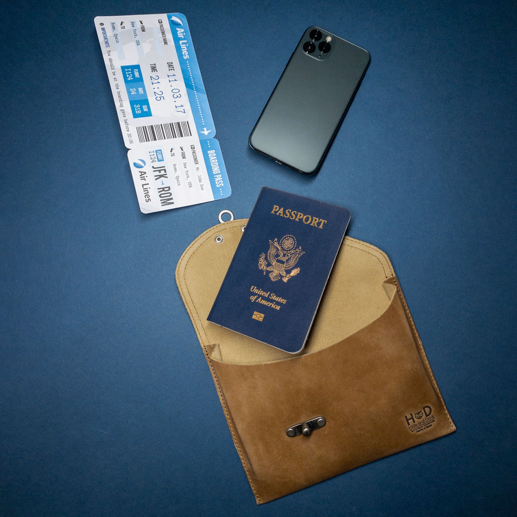 The tan Petite Vintage Clutch Bag by Hide & Drink open with travel essentials, emphasizing its functionality. Crafted from quality full grain leather, this evening bag is a perfect travel accessory for anyone valuing artisan craftsmanship from La Antigua Guatemala & Oaxaca Mexico.