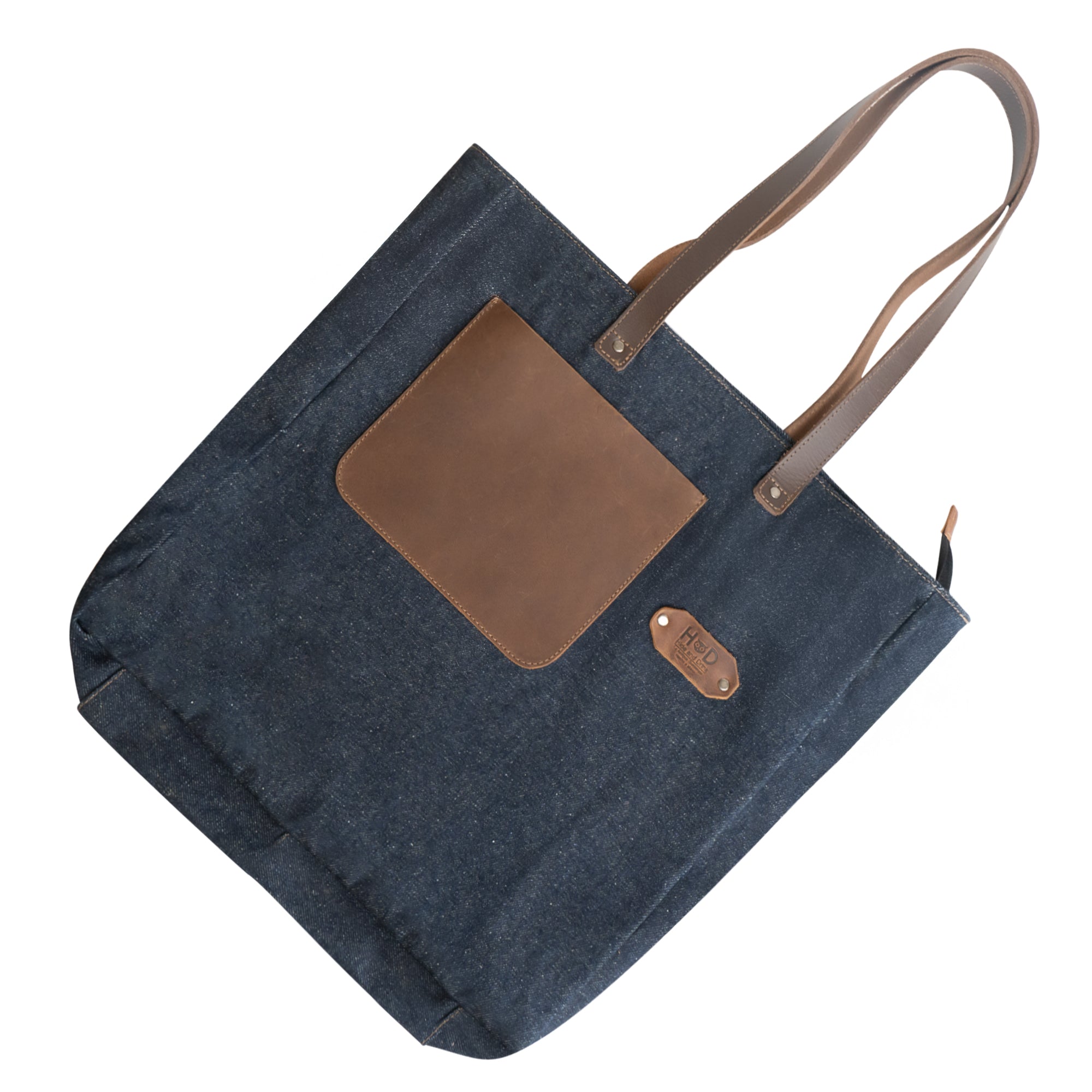 Flat lay of the Denim Tote Bag with Leather Straps by Hide & Drink displaying the exterior design and leather elements. Durable Denim Tote Bag with Leather Straps, Cell Phone Purse, Shoulder Bag for Girls, Full Grain Leather, StockyardX, Small Batch Production, Hand Cut, Hand Sewn, Fire Branded, Artisan, Handmade in La Antigua Guatemala & Oaxaca Mexico.
