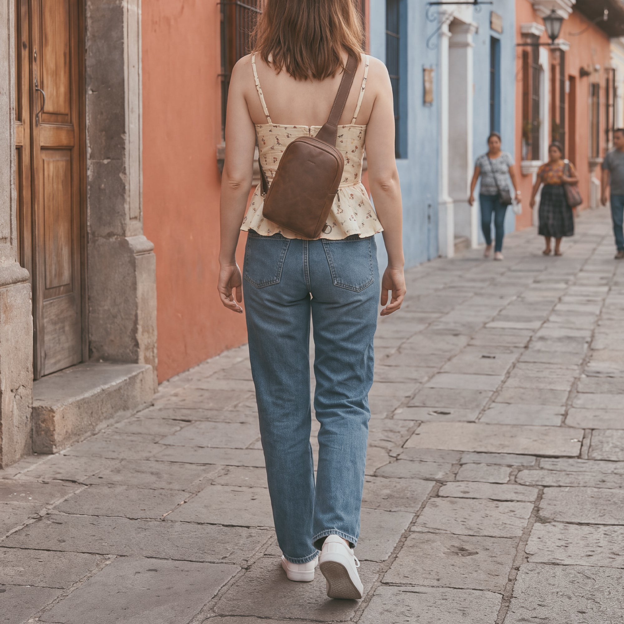 A model wearing the Hide & Drink Crossbody Rounded Bag, demonstrating how to wear this Rounded Crossbody Bag with Adjustable Strap as a stylish messenger bag. Crafted from durable Full Grain Leather, this travel accessory reflects the quality of artisan, handmade creations from La Antigua Guatemala & Oaxaca Mexico.