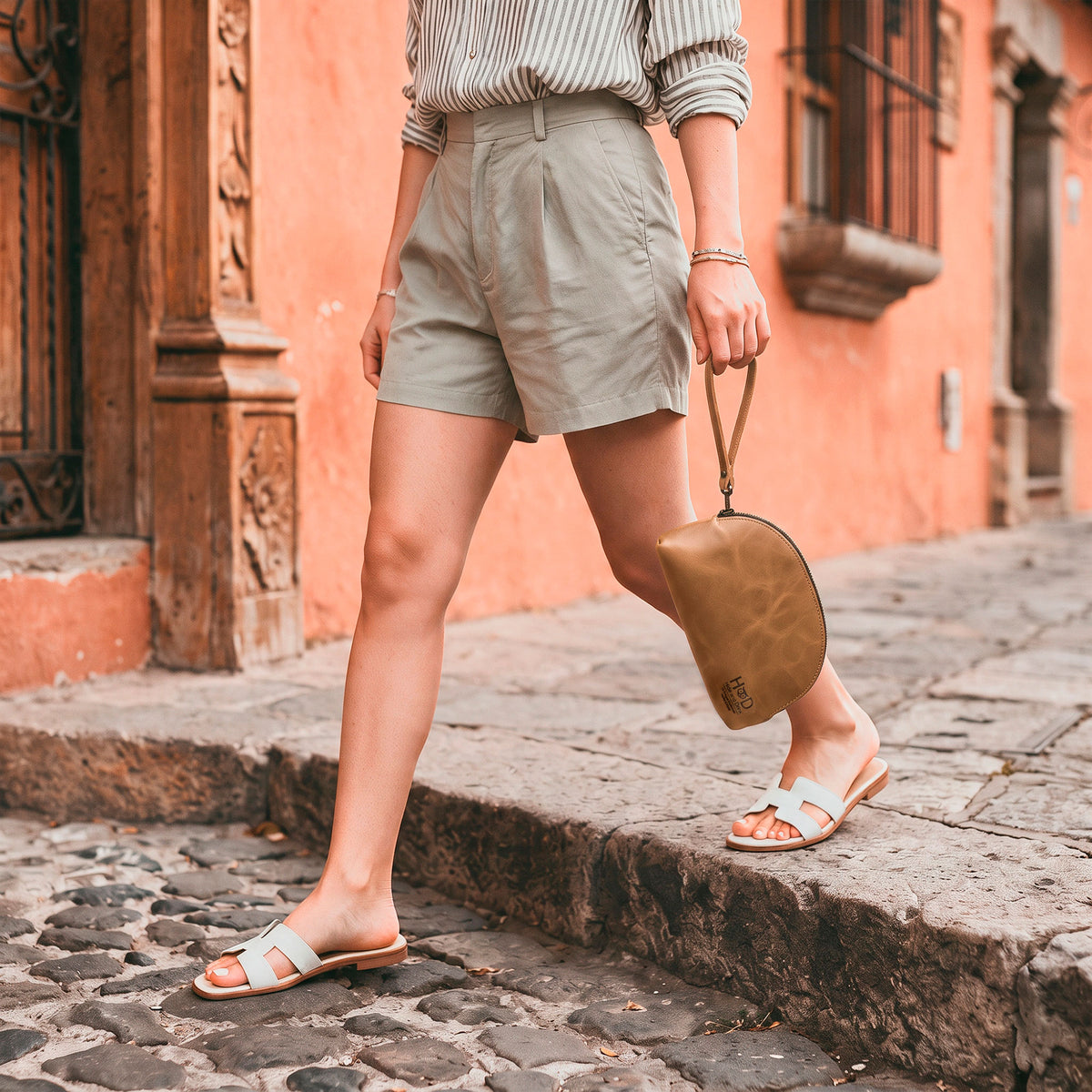 The Accessory Pouch Organizer Hand Bag by Hide & Drink alongside a business card, showcasing artisan craftsmanship in brown full grain leather. This Cosmetic Travel Organizer with Hand Strap for Women serves as an ideal Makeup Bag and Classic Handbag, handmade in La Antigua Guatemala & Oaxaca Mexico.