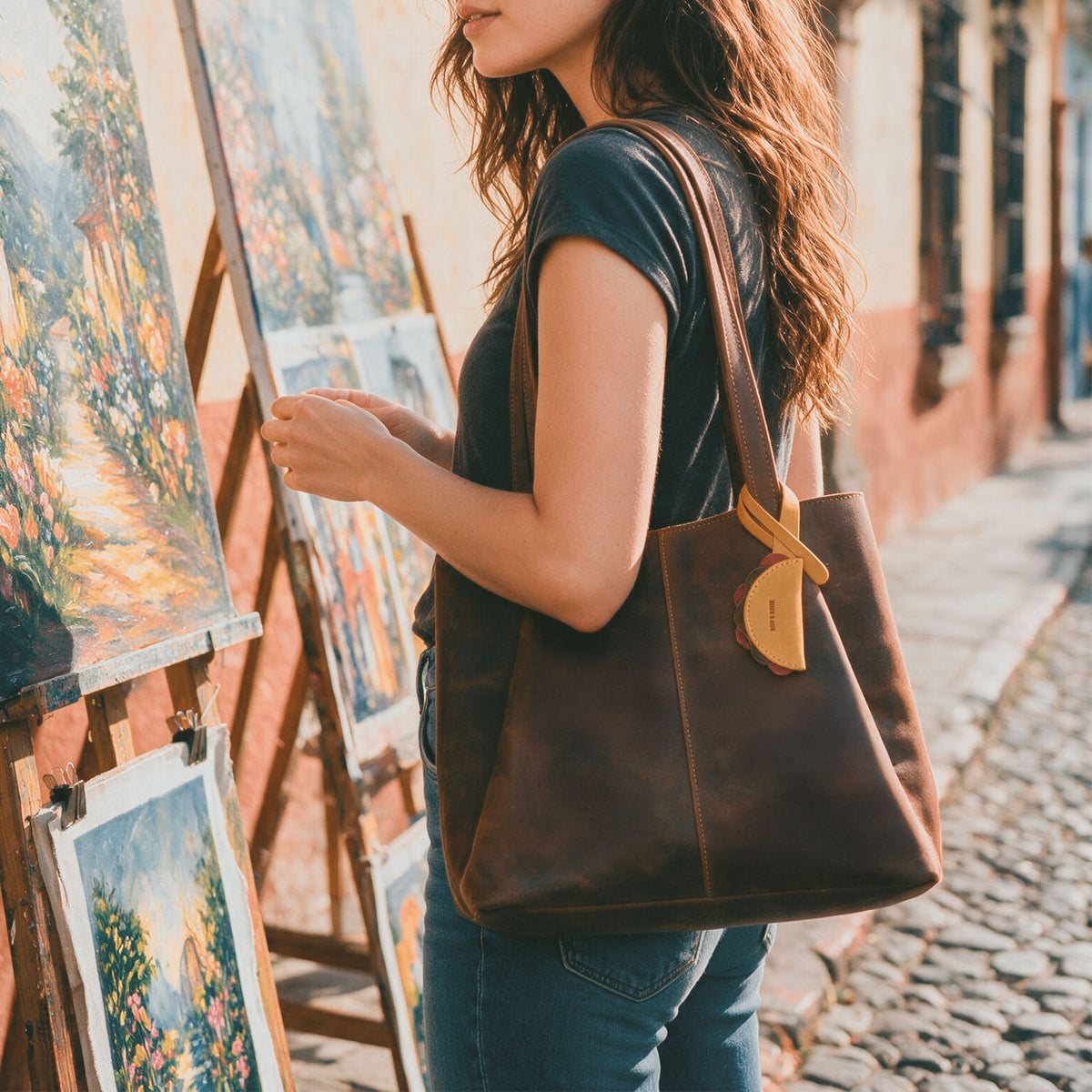 Woman carrying a brown tote decorated with the Hide & Drink Taco Bag Charm, a Full Grain Leather Artisan accessory made with Small Batch Production, Hand Cut, Hand Sewn, and Fire Branded details, Handmade in La Antigua Guatemala & Oaxaca Mexico, from StockyardX.
