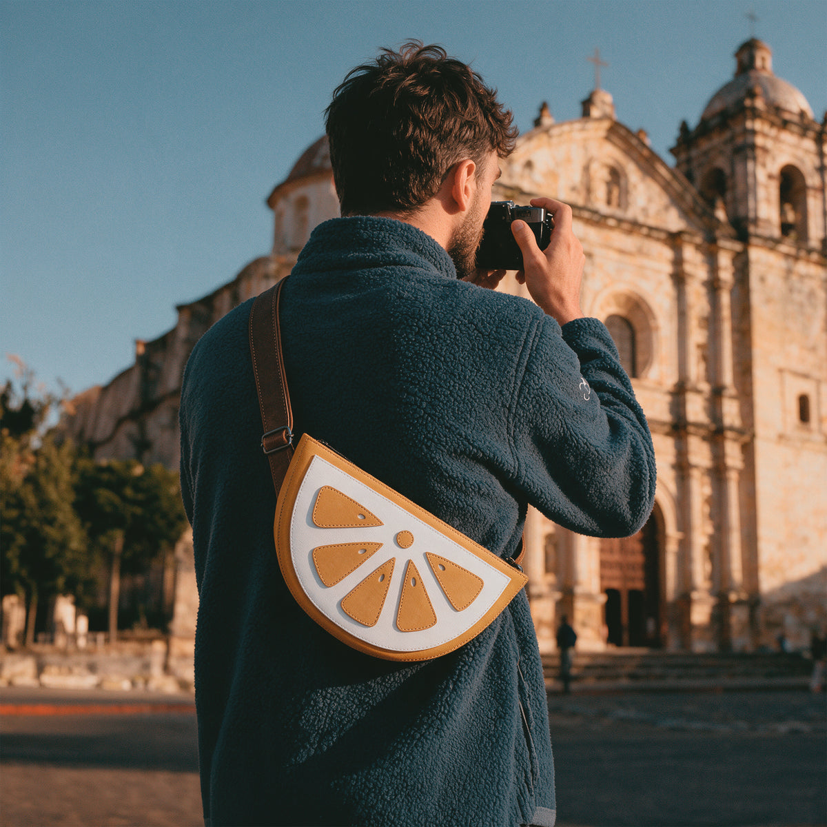 Model wearing the Tudi Frudi Lemon Crossbody Bag as a Shoulder Bag while traveling, featuring Full Grain Leather and a playful lemon design created for StockyardX with Small Batch Production, Hand Cut, Hand Sewn, Fire Branded, Artisan craftsmanship, Handmade in La Antigua Guatemala & Oaxaca Mexico.