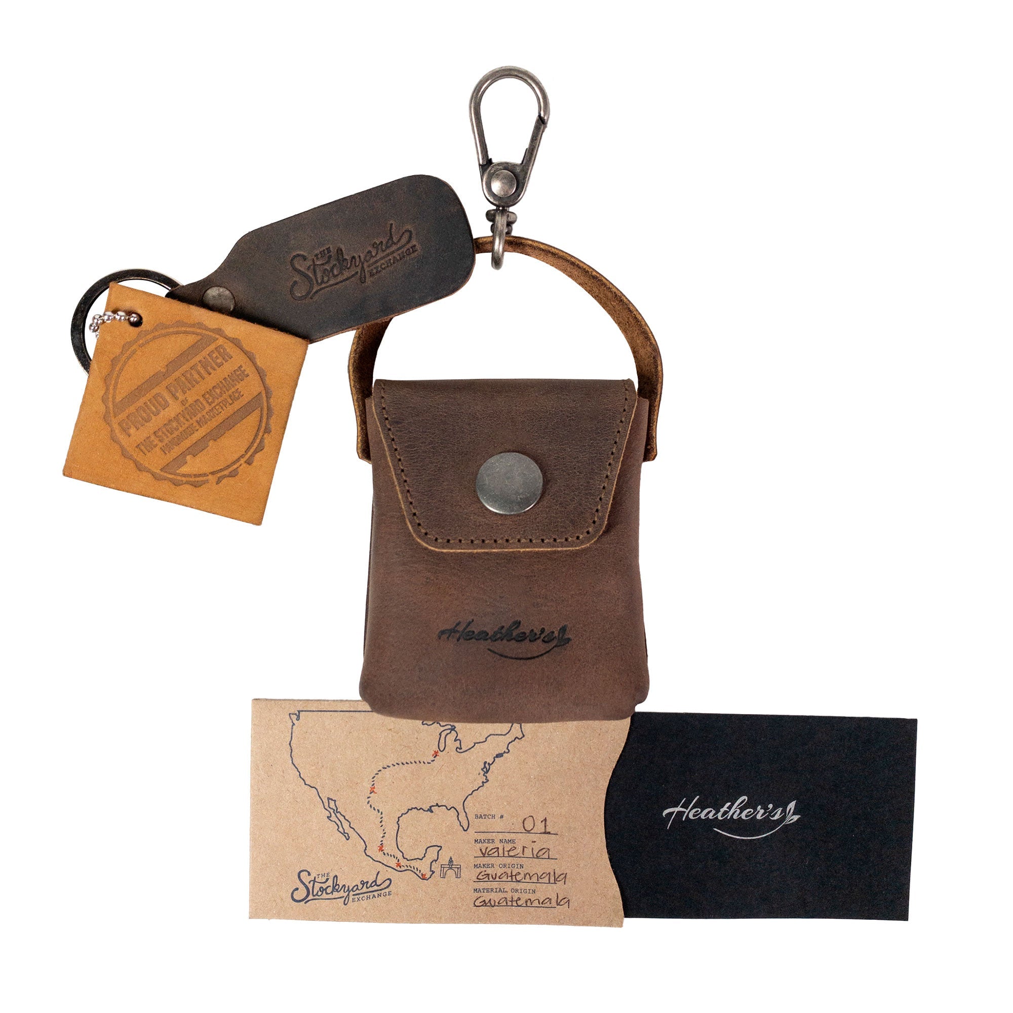 Heather's Mini Purse-Shaped Keychain paired with additional tags and branding. This full grain leather vintage keyring holder serves as a functional mini purse keychain for women, crafted through artisan techniques in La Antigua Guatemala & Oaxaca Mexico.
