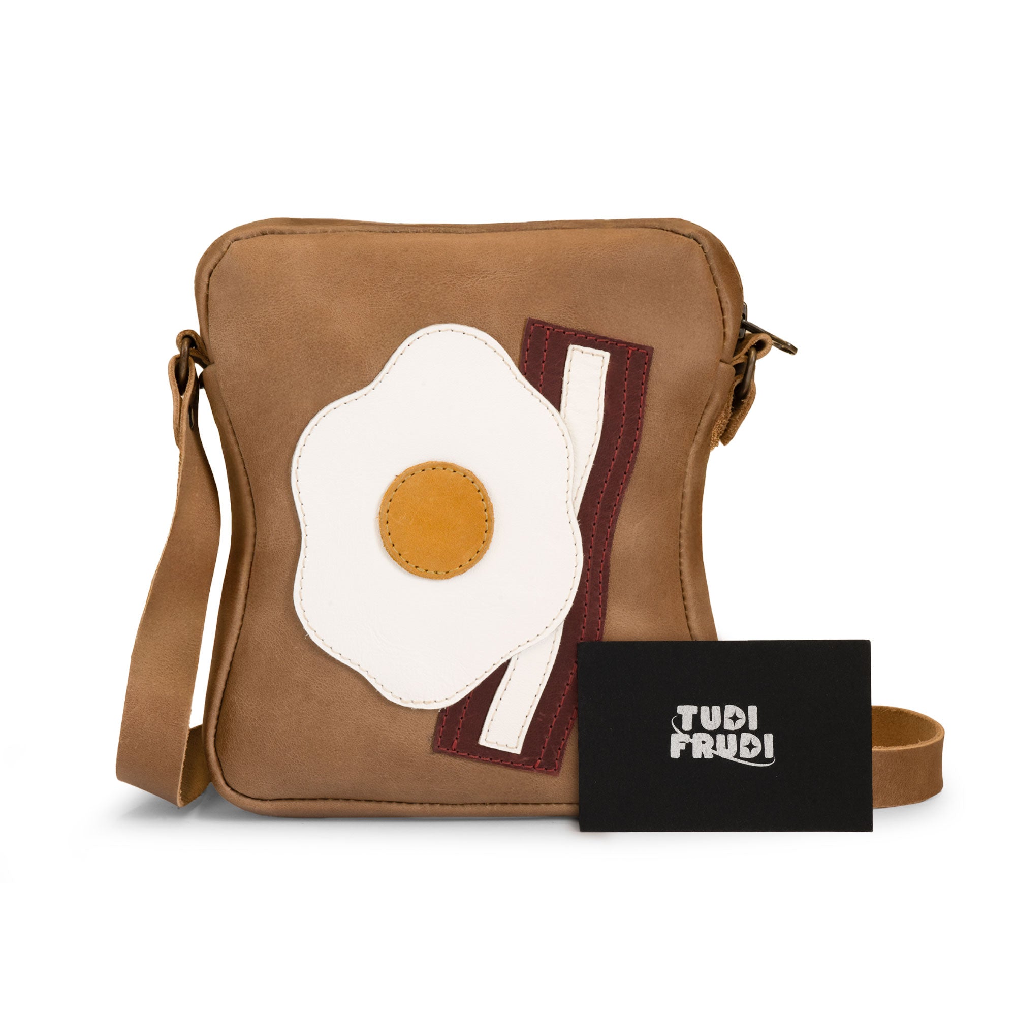 The Egg and Bacon Sandwich-Shaped Shoulder Bag by Tudi Frudi, adorned with tags highlighting its artisan craftsmanship. This versatile Handbag, Crossbody Bag, or Messenger Bag is made from Full Grain Leather, emphasizing small batch production techniques, Handmade in La Antigua Guatemala & Oaxaca Mexico.