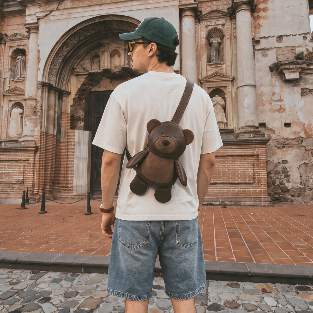 Lifestyle image of a person wearing the Tudi Frudi Leather Teddy Bear Crossbody Bag over one shoulder, showing its playful brown bear design and Adjustable Shoulder Strap for Messenger Bag, Shoulder Bag, Zippered Sling Bags, Travel Backpack, Purses for Men and Women, and Satchel use, crafted in Full Grain Leather by StockyardX with Small Batch Production, Hand Cut, Hand Sewn, Fire Branded, Artisan, Handmade in La Antigua Guatemala & Oaxaca Mexico.