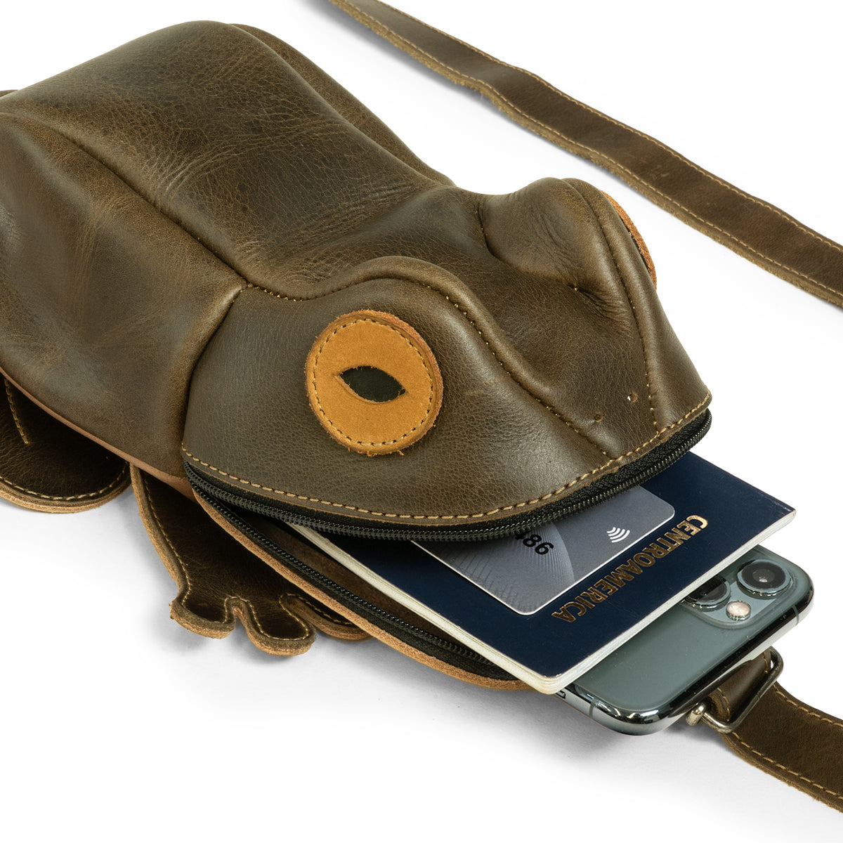Close-up of the Tudi Frudi Frog Crossbody holding a smartphone and passport, showing its secure zipper and Full Grain Leather finish; this Frog Crossbody Bag with Adjustable Shoulder Strap is also a Messenger Bag, Shoulder Bag, Zippered Sling Bags, Travel Backpack, Purses for Men and Women, and Satchel, made by StockyardX through Small Batch Production, Hand Cut, Hand Sewn, Fire Branded, Artisan, Handmade in La Antigua Guatemala & Oaxaca Mexico.