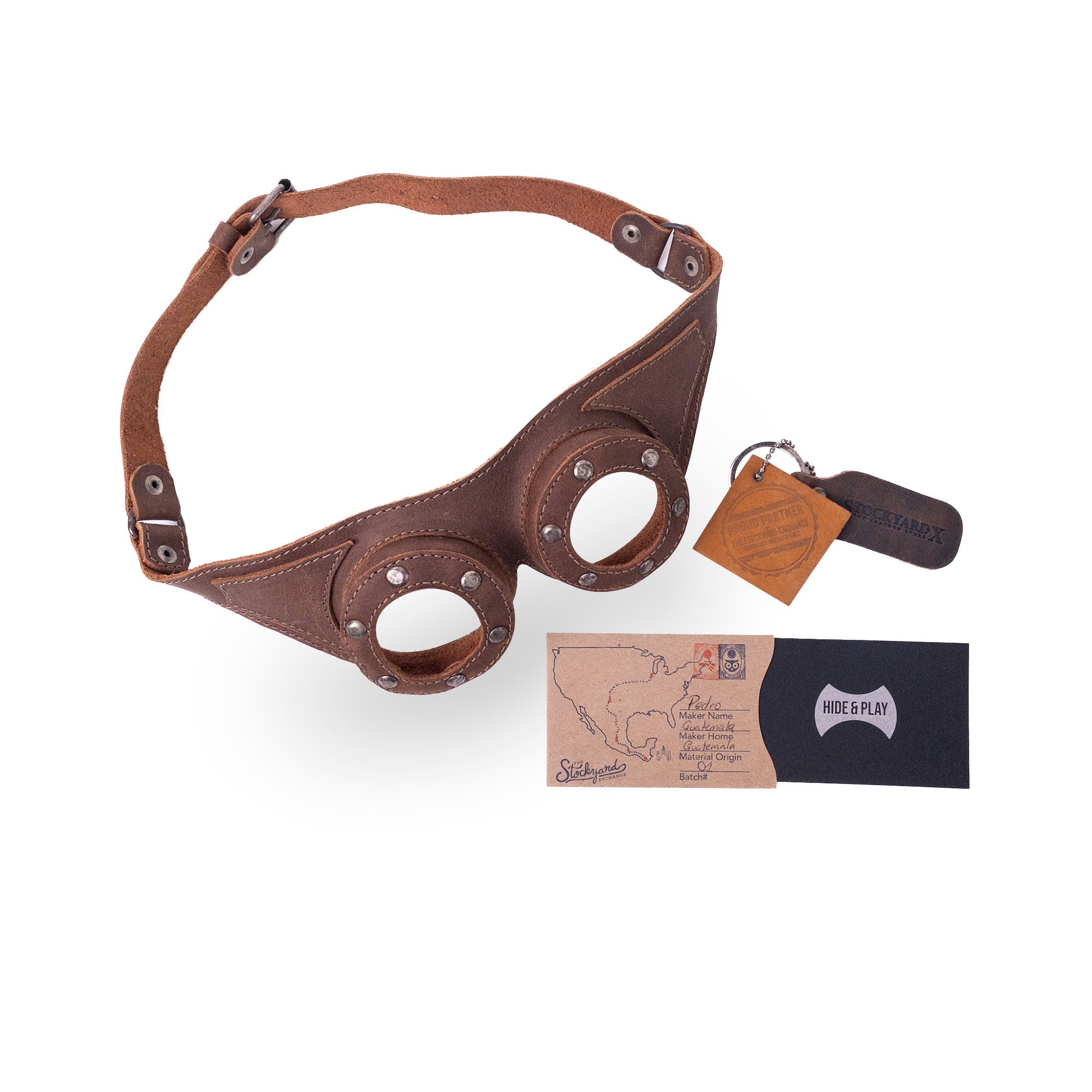 Complete package of Riveted Steampunk Goggles by Hide & Play, featuring the goggles, care card, and branding. Handmade in La Antigua Guatemala, these full grain leather goggles are a must-have for steampunk enthusiasts and retro cosplay lovers.