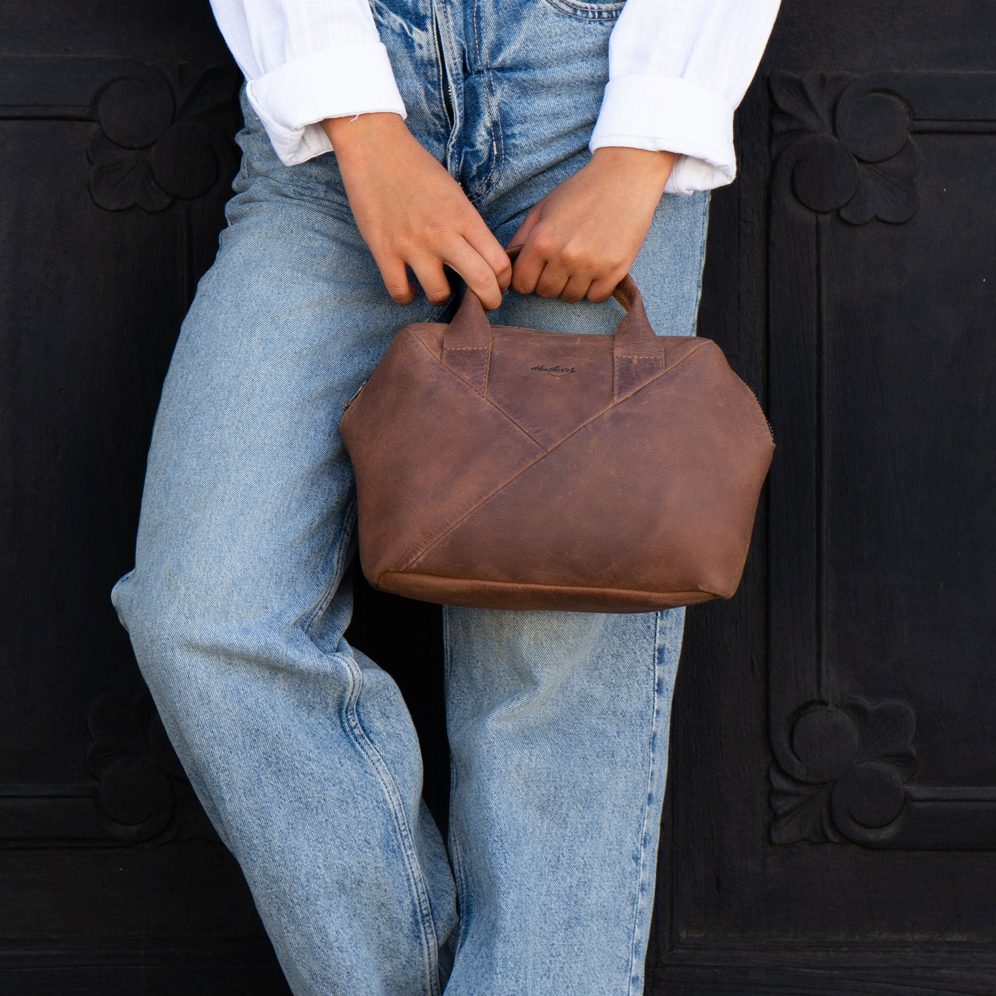 A model holding Heather's Fluffy Purse made of Full Grain Leather. This versatile Leather Fluffy Purse is ideal as a Handbag for Women, functioning beautifully as a Night Bag, or a Rectangular Purse with Zipper for organization. With its artisan craftsmanship from Small Batch Production, it's Hand Cut, Hand Sewn, Fire Branded, and proudly Handmade in La Antigua Guatemala & Oaxaca Mexico.