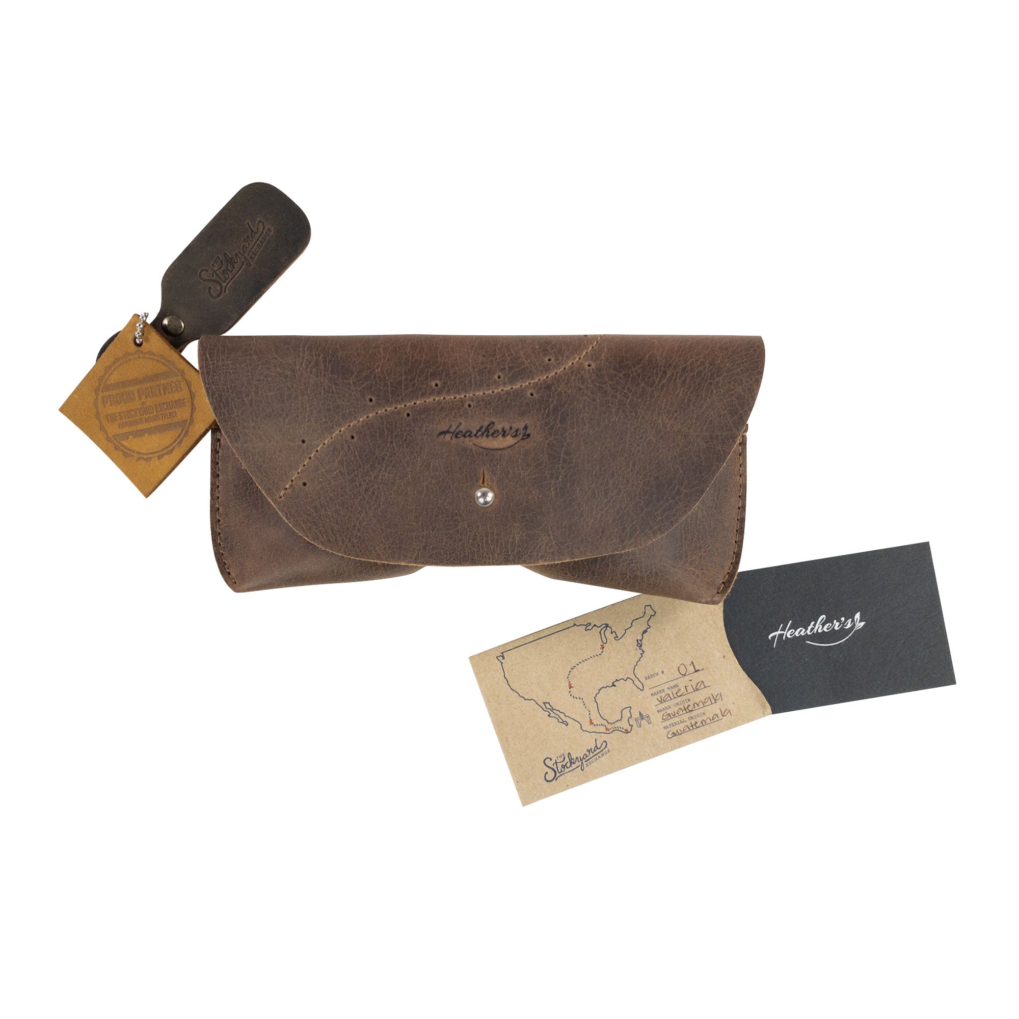 Heather's Eyeglasses Case alongside branding materials, showcasing its authenticity and quality. This full grain leather sunglasses sleeve is a testament to small batch production and artisan craftsmanship from La Antigua Guatemala.