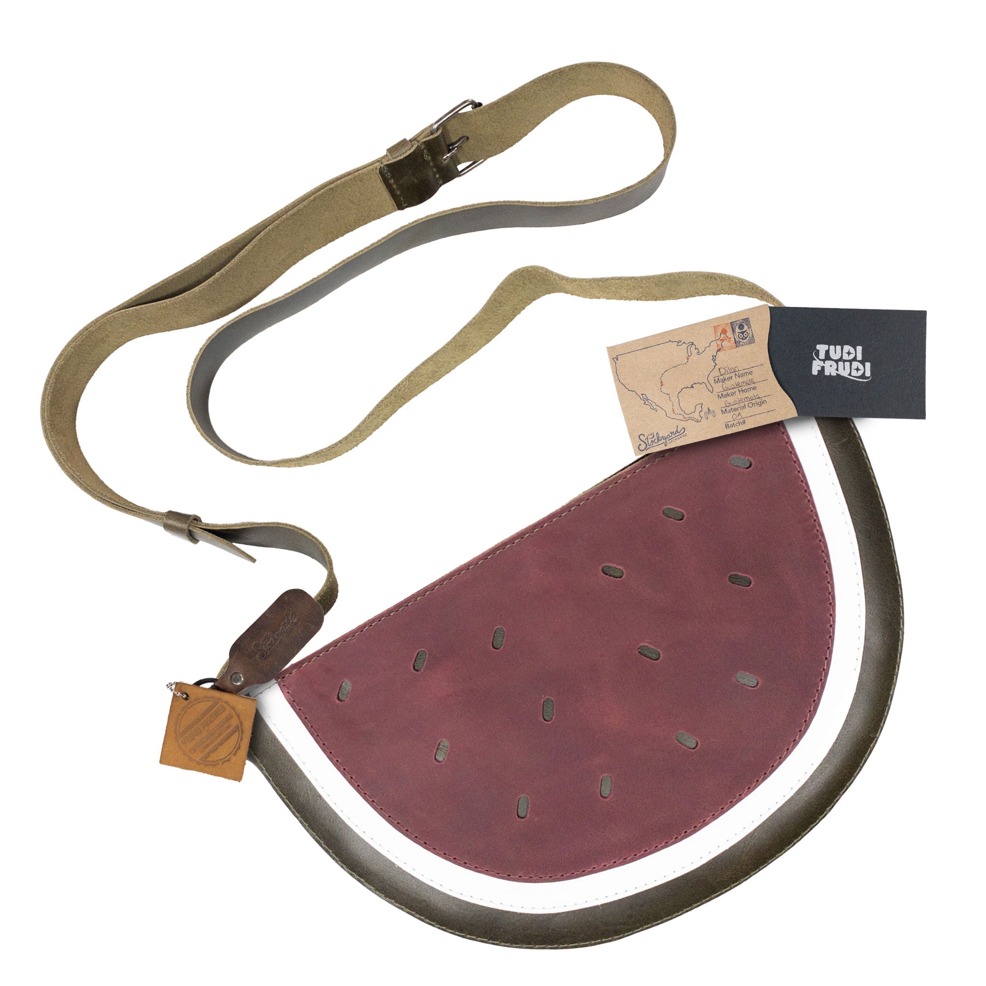 Detailed view of the Watermelon-Shaped Shoulder Bag by Tudi Frudi with tags showing its artisan origin. This eye-catching Crossbody Bag and Messenger Bag is made from high-quality Full Grain Leather and showcases the brand's dedication to small batch production, hand cut, hand sewn, and fire branded craftsmanship. Handmade in La Antigua Guatemala & Oaxaca Mexico.