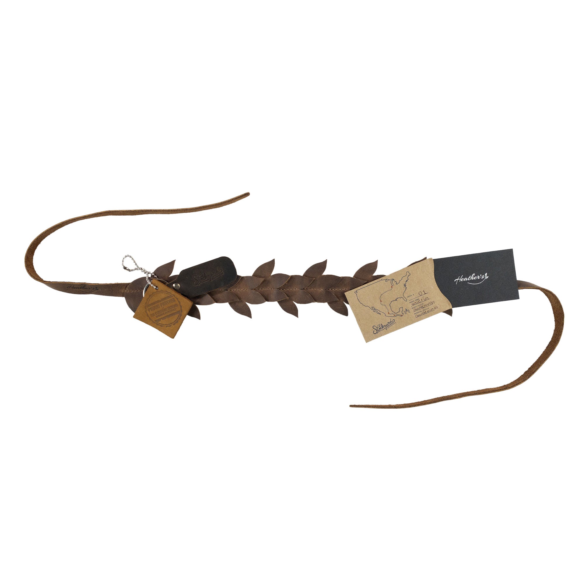 Styled flat lay of Heather's Flowered Headband with accompanying tags, showcasing its rustic charm and full grain leather material. This flower crown for women emphasizes small batch production, beautifully hand cut and hand sewn, celebrating artisan craftsmanship from La Antigua Guatemala.