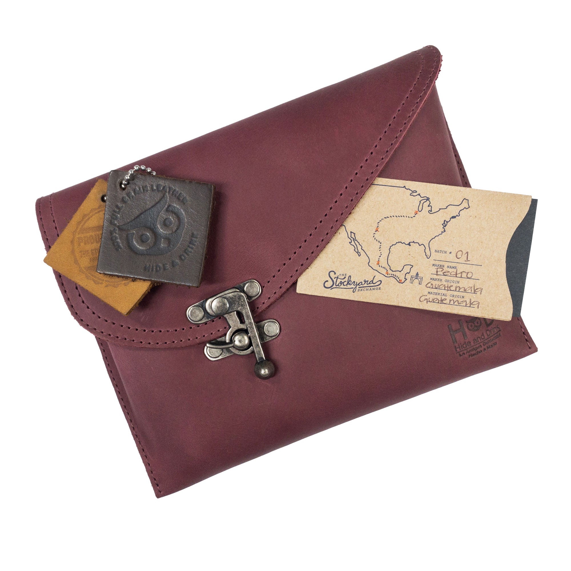 The Petite Vintage Clutch Bag by Hide & Drink alongside personal items, showcasing its versatility. This full grain leather handbag is perfect for outings as an elegant evening bag or travel accessory. Celebrate artisan craftsmanship with this handmade product from La Antigua Guatemala & Oaxaca Mexico.