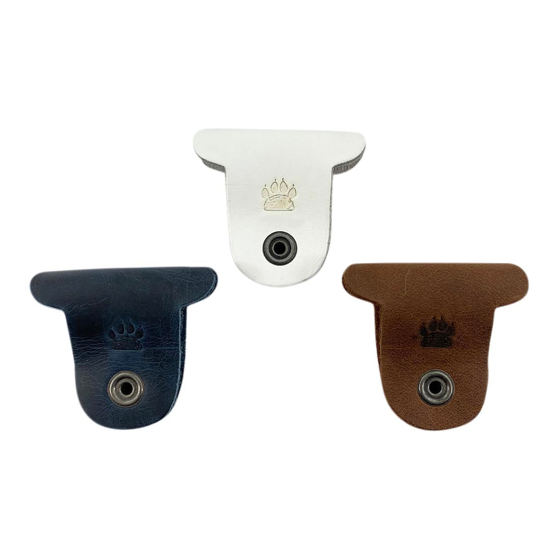 Multicolor Dog Cord Keeper (3 Pack) by Taco Dog showcasing a close-up of three charming dog-shaped cord keepers in varying leather shades, ideal for organizing your accessories. Dog Cord Keeper - Wrap Up Your Cables, Earbuds, Headphones, Chargers - Clip The Straps Together for Easy Management and Travel - 3-Pack, Full Grain Leather, StockyardX, Small Batch Production, Hand Cut, Hand Sewn, Fire Branded, Artisan, Handmade in La Antigua Guatemala & Oaxaca Mexico.