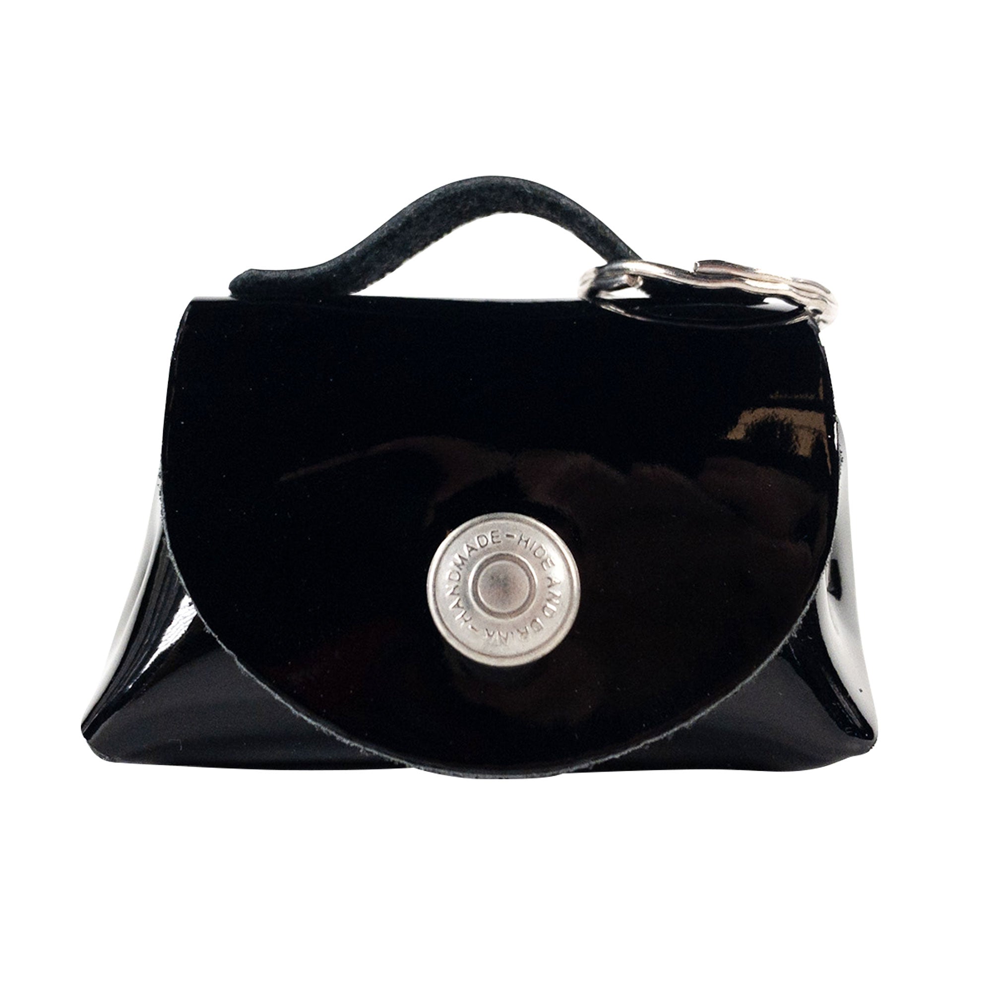 Front view of the glossy black Tiny Handbag Keychain by Hide & Drink, with a shiny finish and key ring holder. Made from Full Grain Leather, this piece embodies the artisan craftsmanship associated with small batch production.